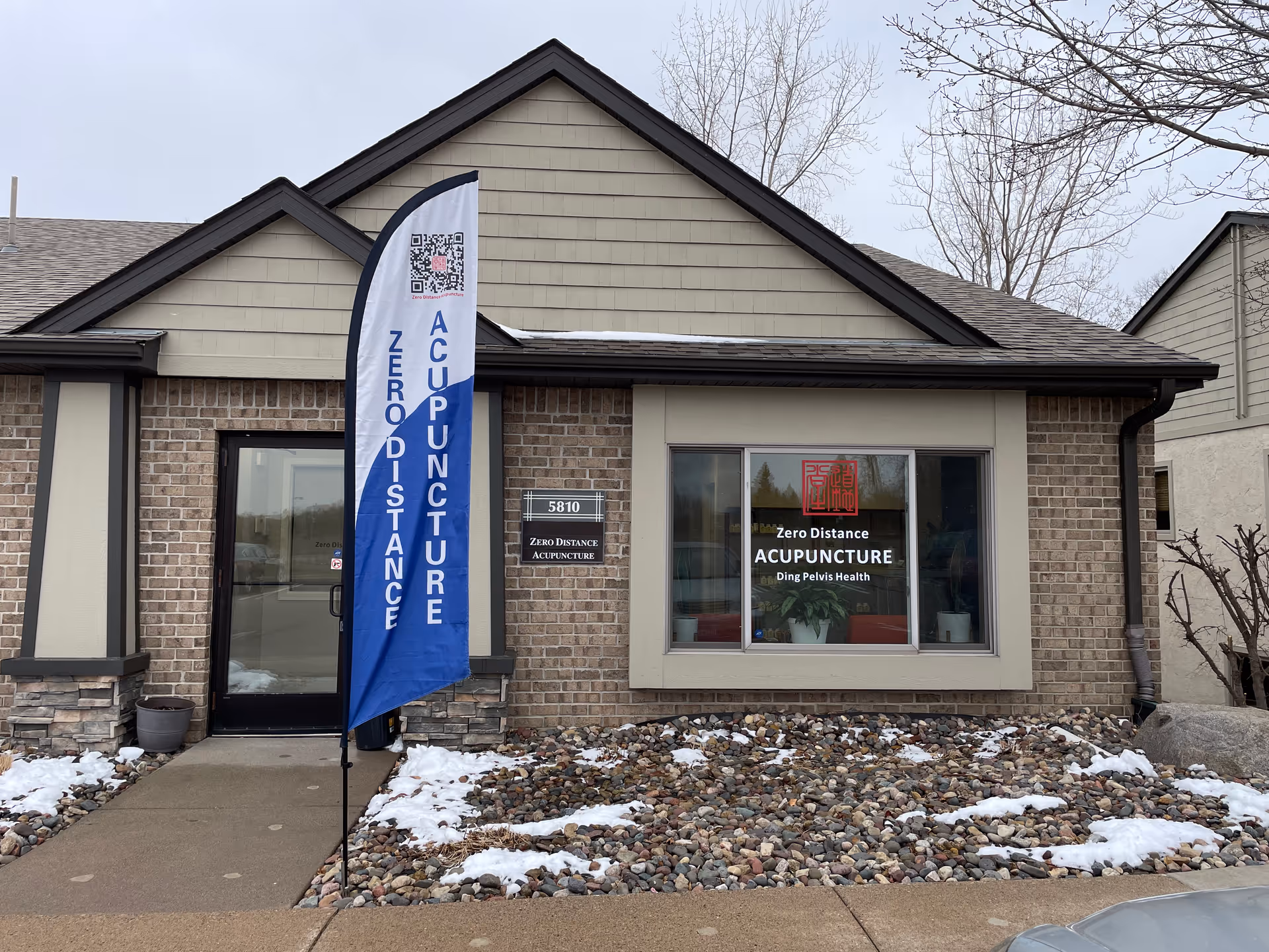 Front exterior of a brick building with a blue banner reading Zero Distance Acupuncture.