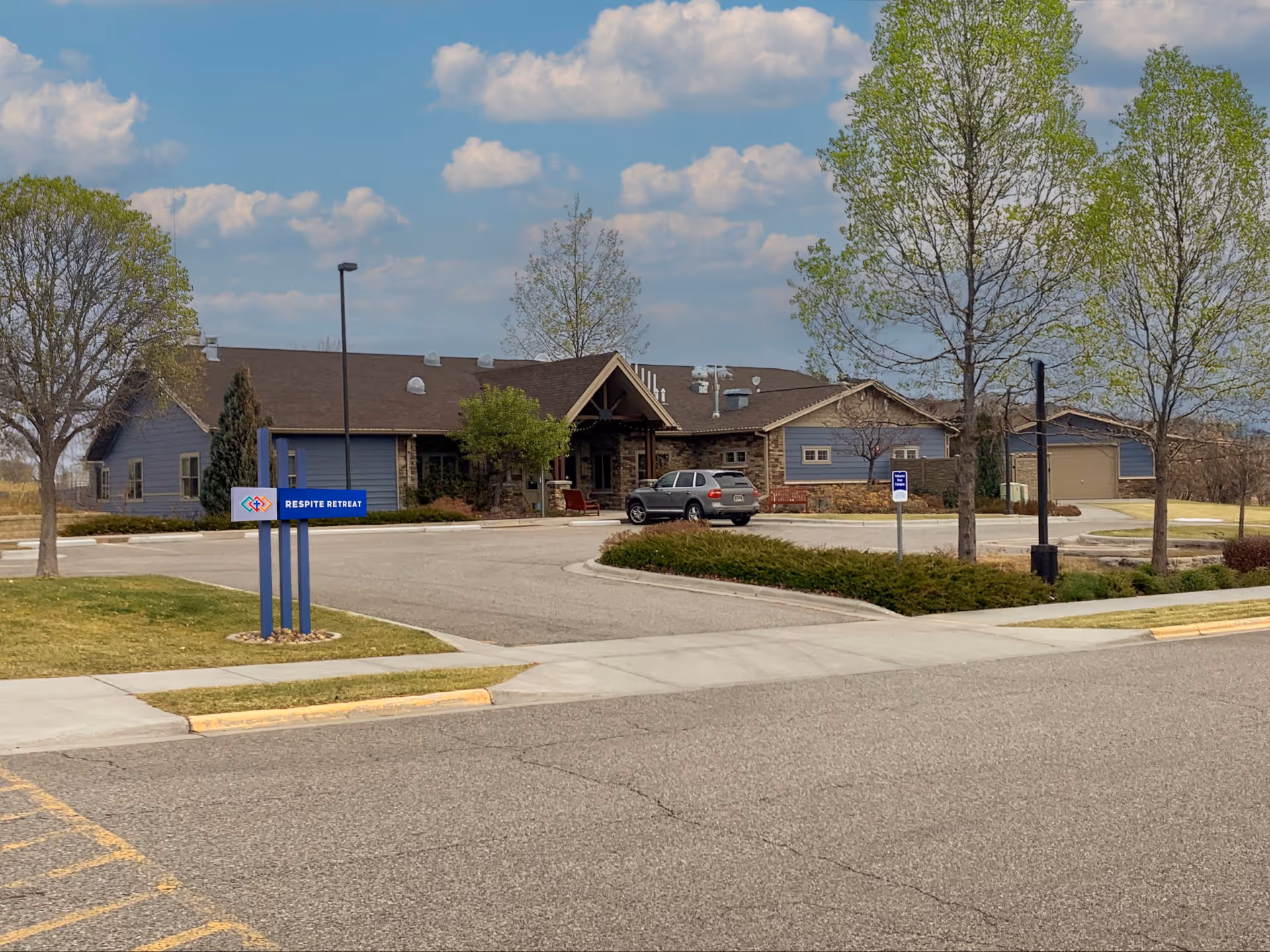Exterior view of St. John's United Respite Suites with parking and trees