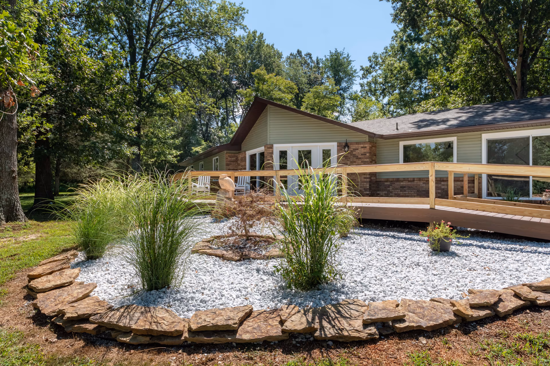 Single-story senior living facility exterior featuring a wooden deck and landscaped rock garden.