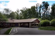 Front exterior of Luther Woods Nursing and Rehabilitation Center with driveway and trees.