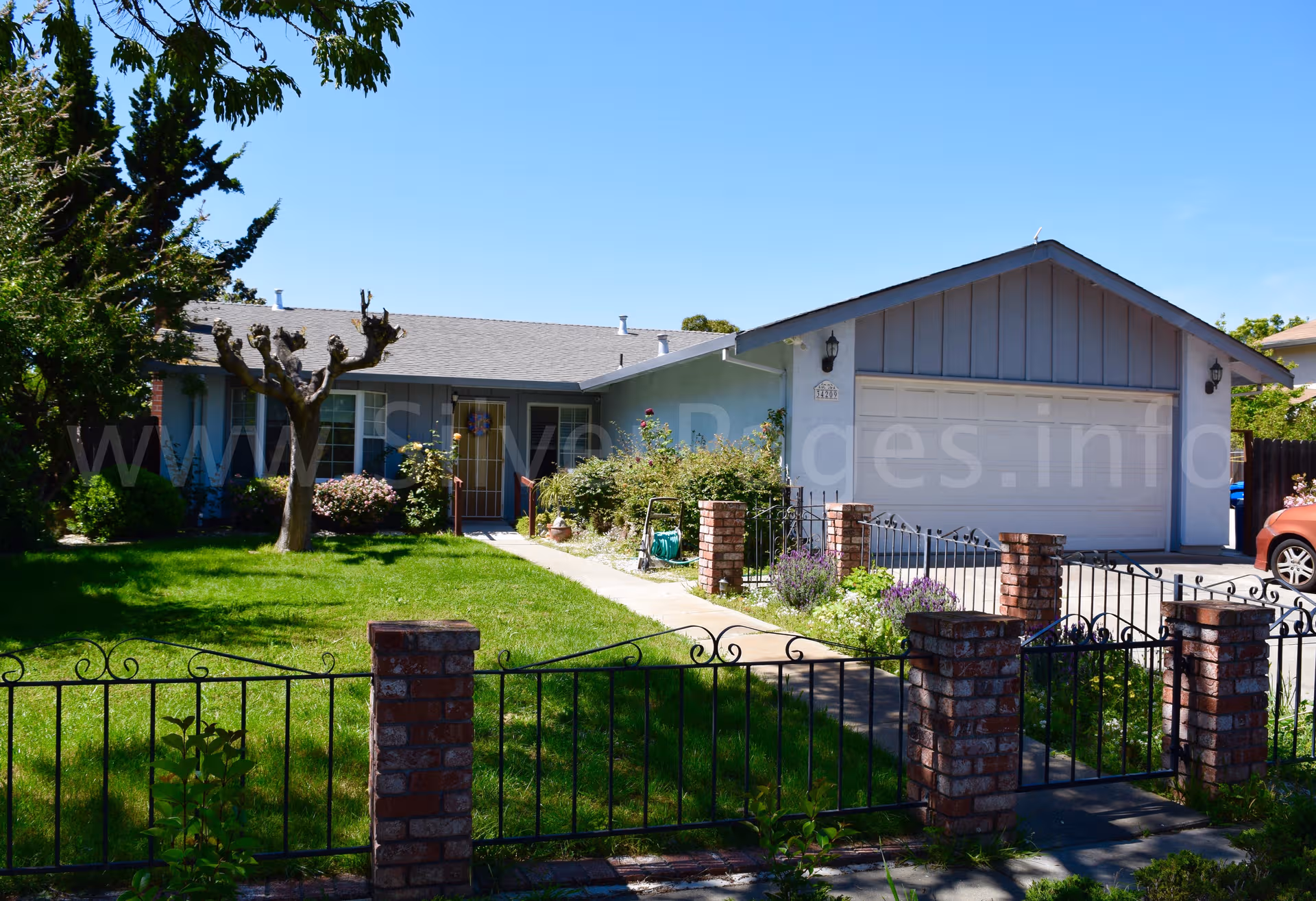 Front view of a single-story care home with a fenced lawn and driveway.