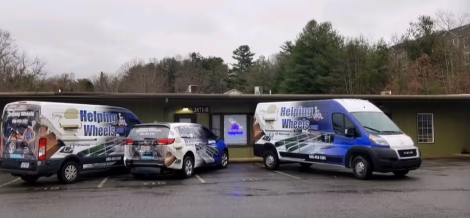 Three Helping Wheels Inc vans parked in front of a single-story facility.