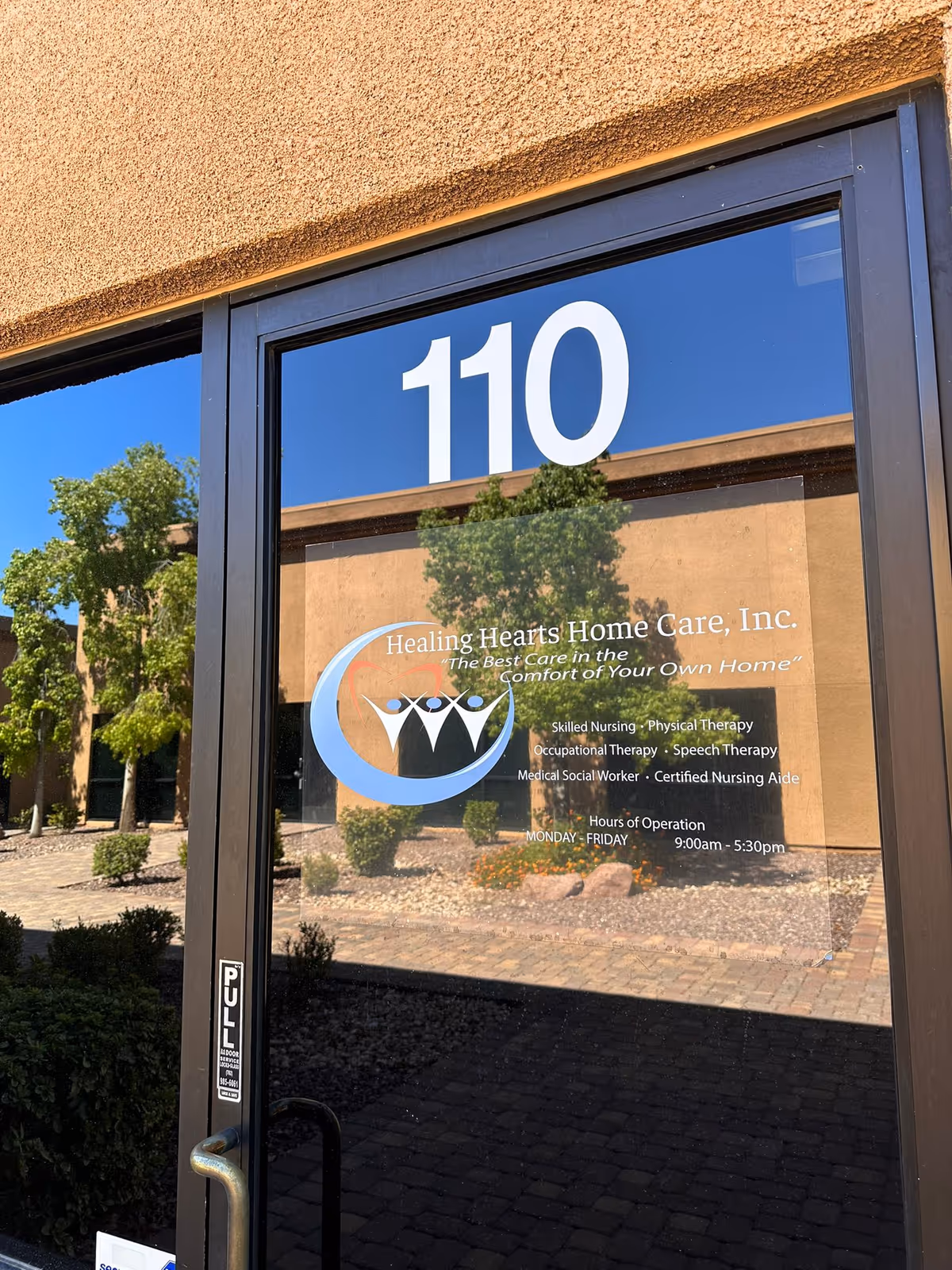 Exterior glass door labeled 110 with Healing Hearts Home Care sign.