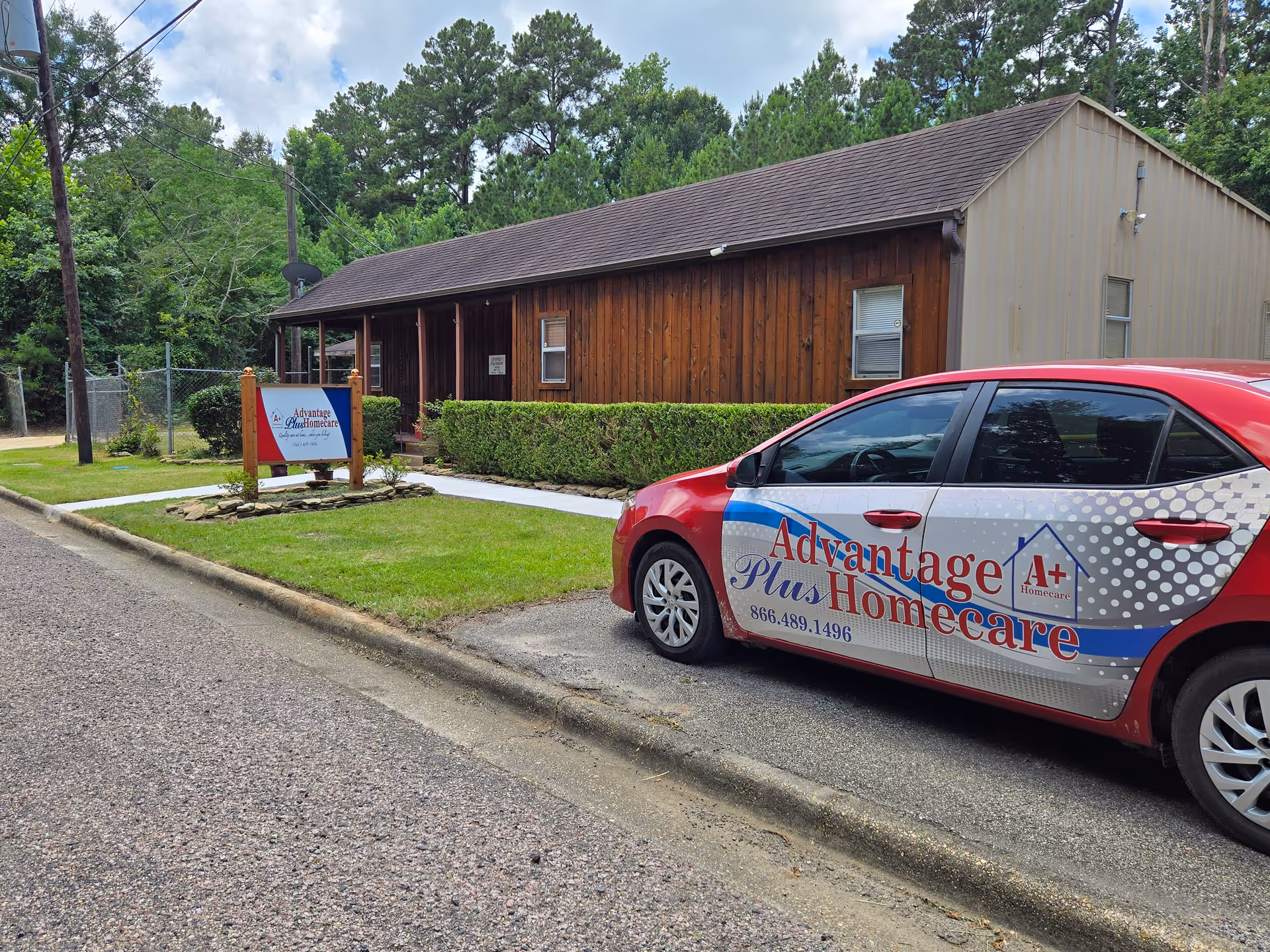 Exterior view of Advantage Plus Homecare building with a branded car parked outside.