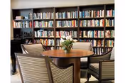 Round wooden table with four striped chairs in a library lounge; flowers.