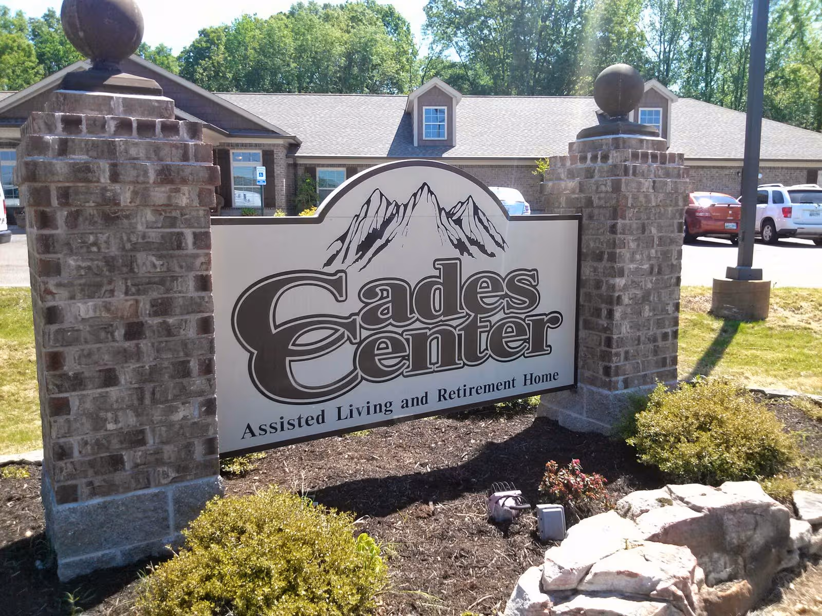 Outdoor entrance sign for Cades Center Assisted Living with brick columns.