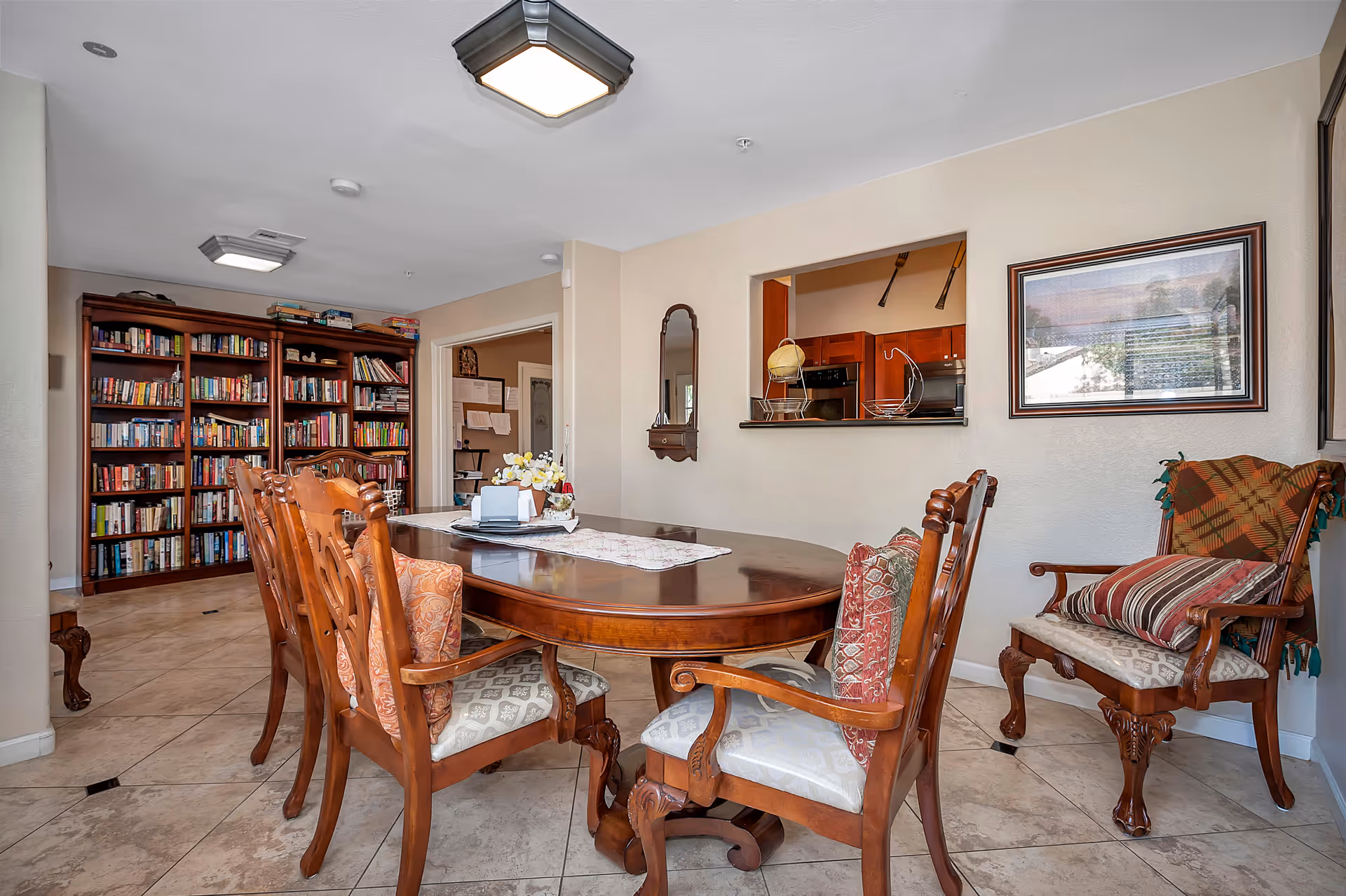 Interior dining area with a round wooden table, chairs, and tall bookshelves.