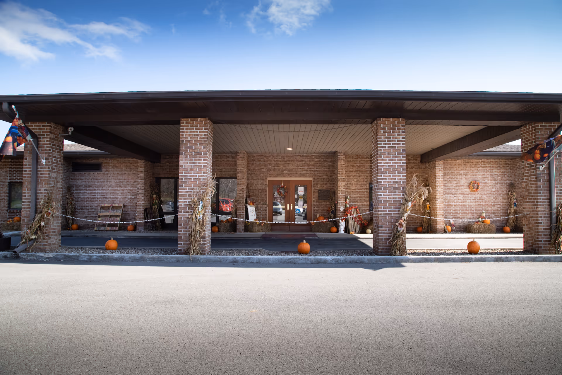 Front entrance of Autumn Lake Healthcare at Crystal Springs with brick columns and fall pumpkins