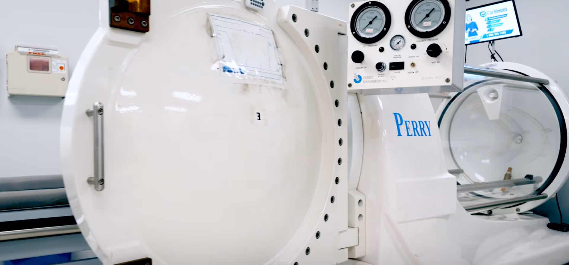 Hyperbaric oxygen chamber with gauges in a bright clinical room.