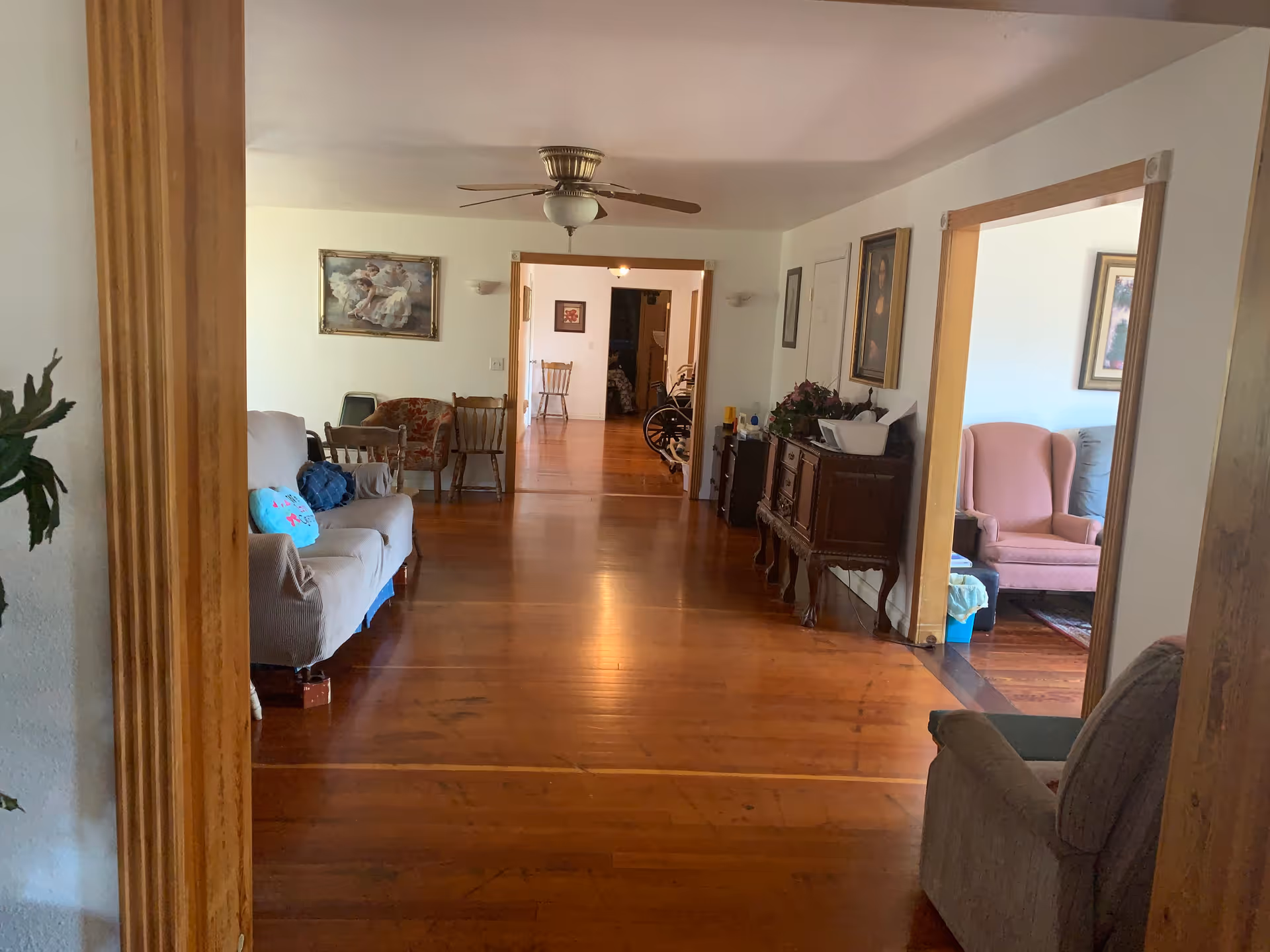Long wooden-floored interior hallway of a senior living facility with seating along the walls.