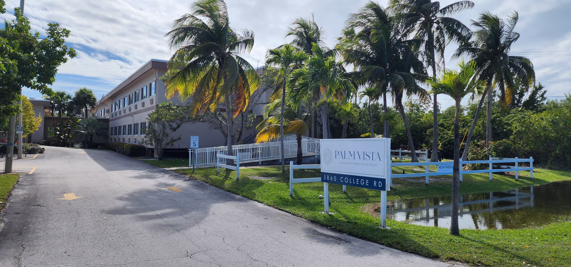 Exterior view of Palm Vista Nursing and Rehabilitation Center with palm trees and a sign.