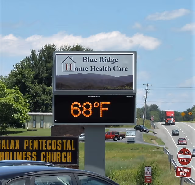Outdoor sign for Blue Ridge Home Health Care beside road with digital temperature display.