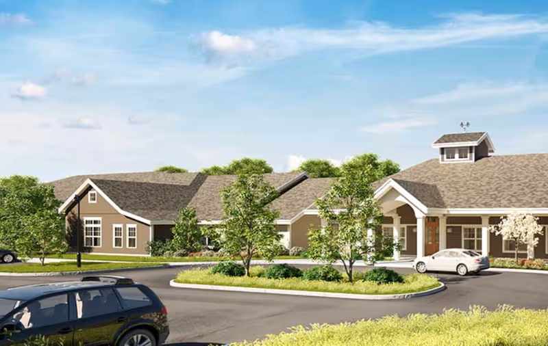 Exterior view of Bridges by EPOCH at Andover, a senior living facility with trees and cars.