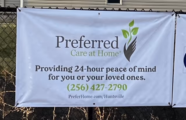 Outdoor banner advertising Preferred Care at Home on a chain-link fence.