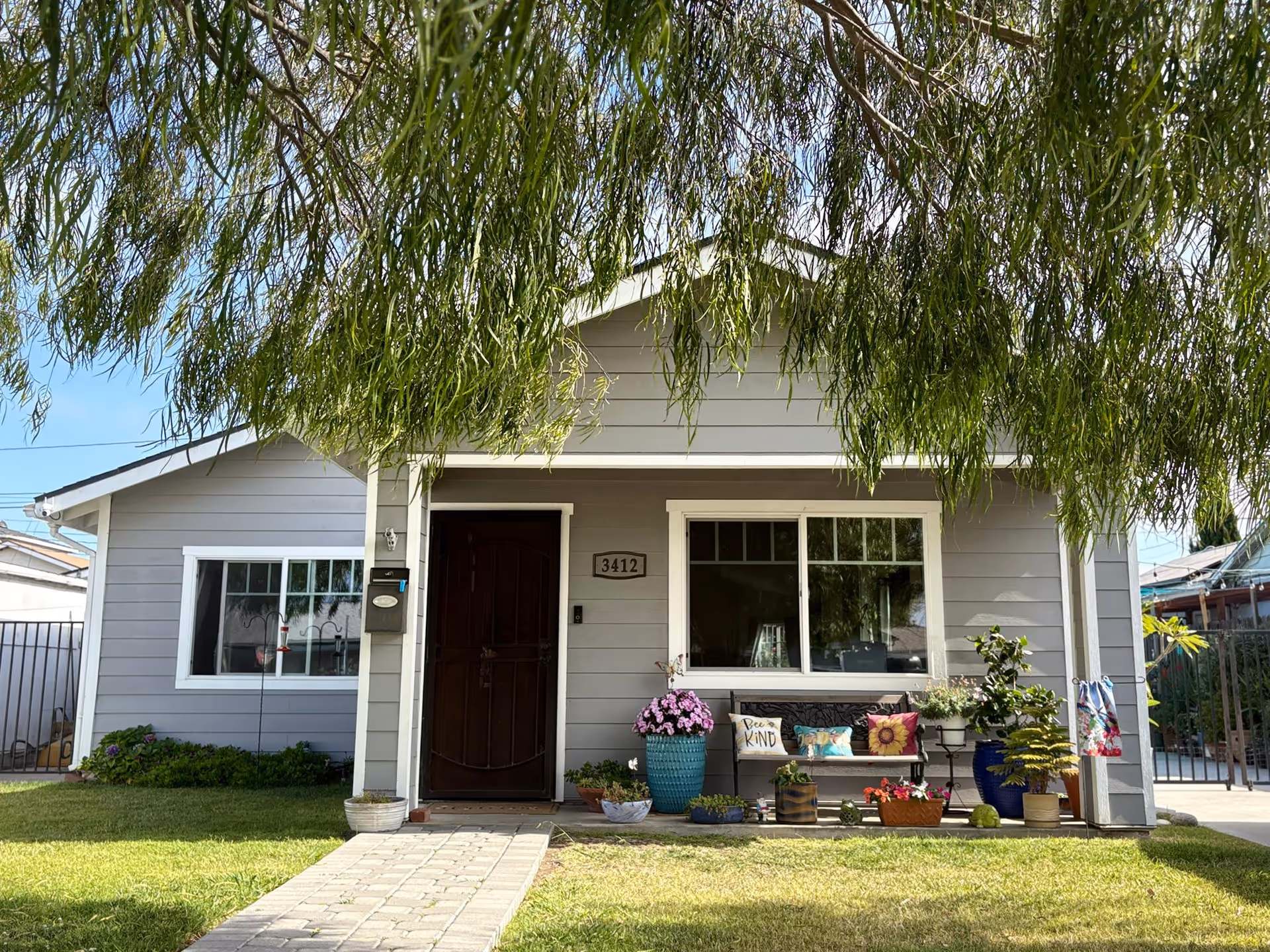 Front view of a gray, house-style Active Board + Care facility with plants and a porch.