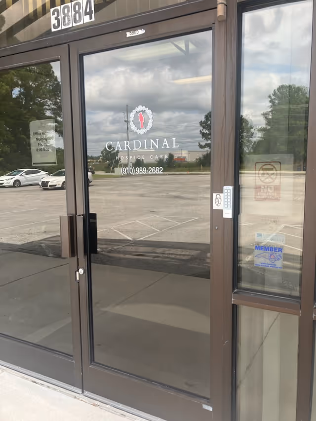 Glass front entrance of Cardinal Hospice Care with door numbers and signage.