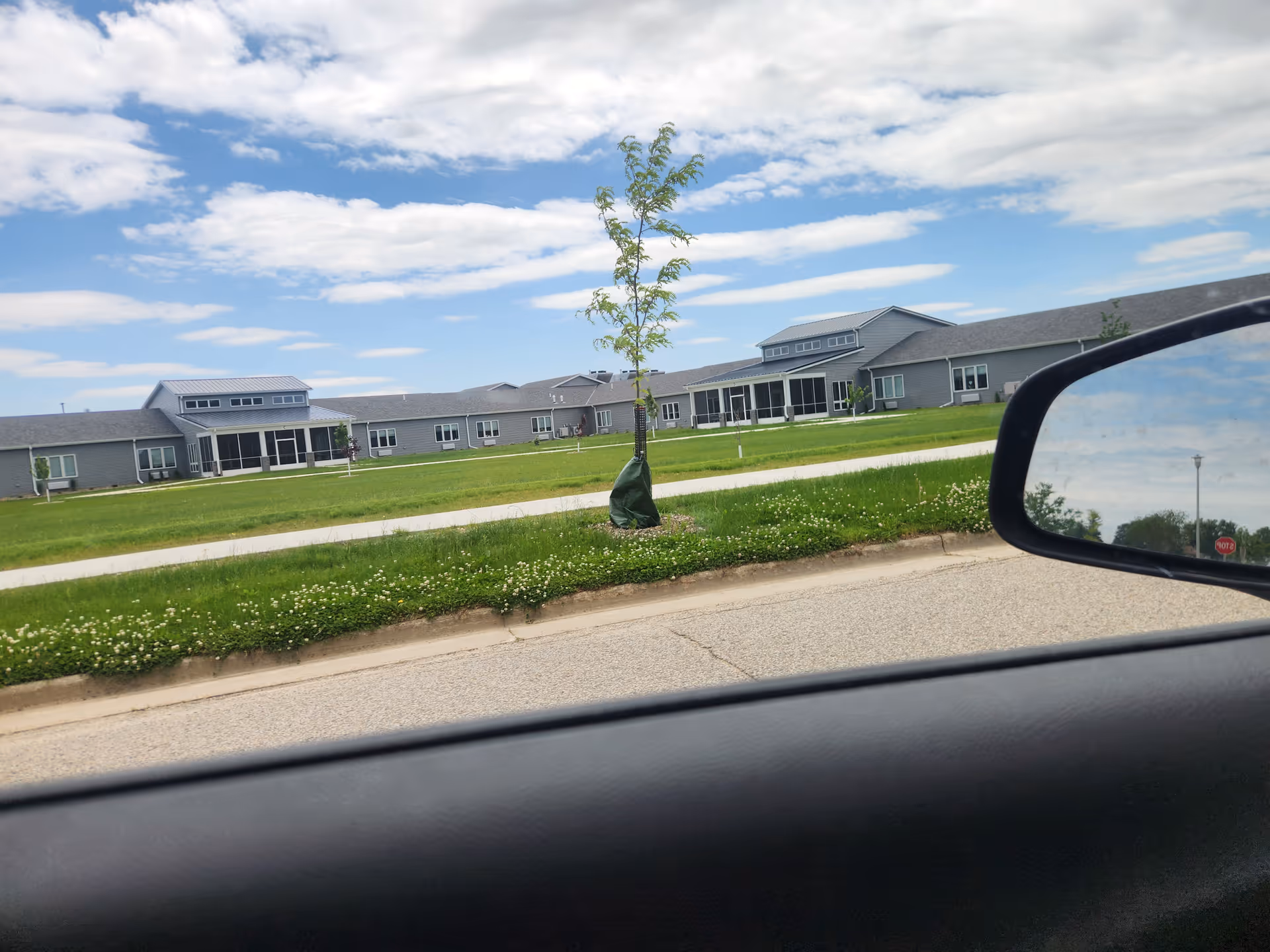 Exterior view of Aase Haugen Homes facility with lawn, trees, and clear sky.