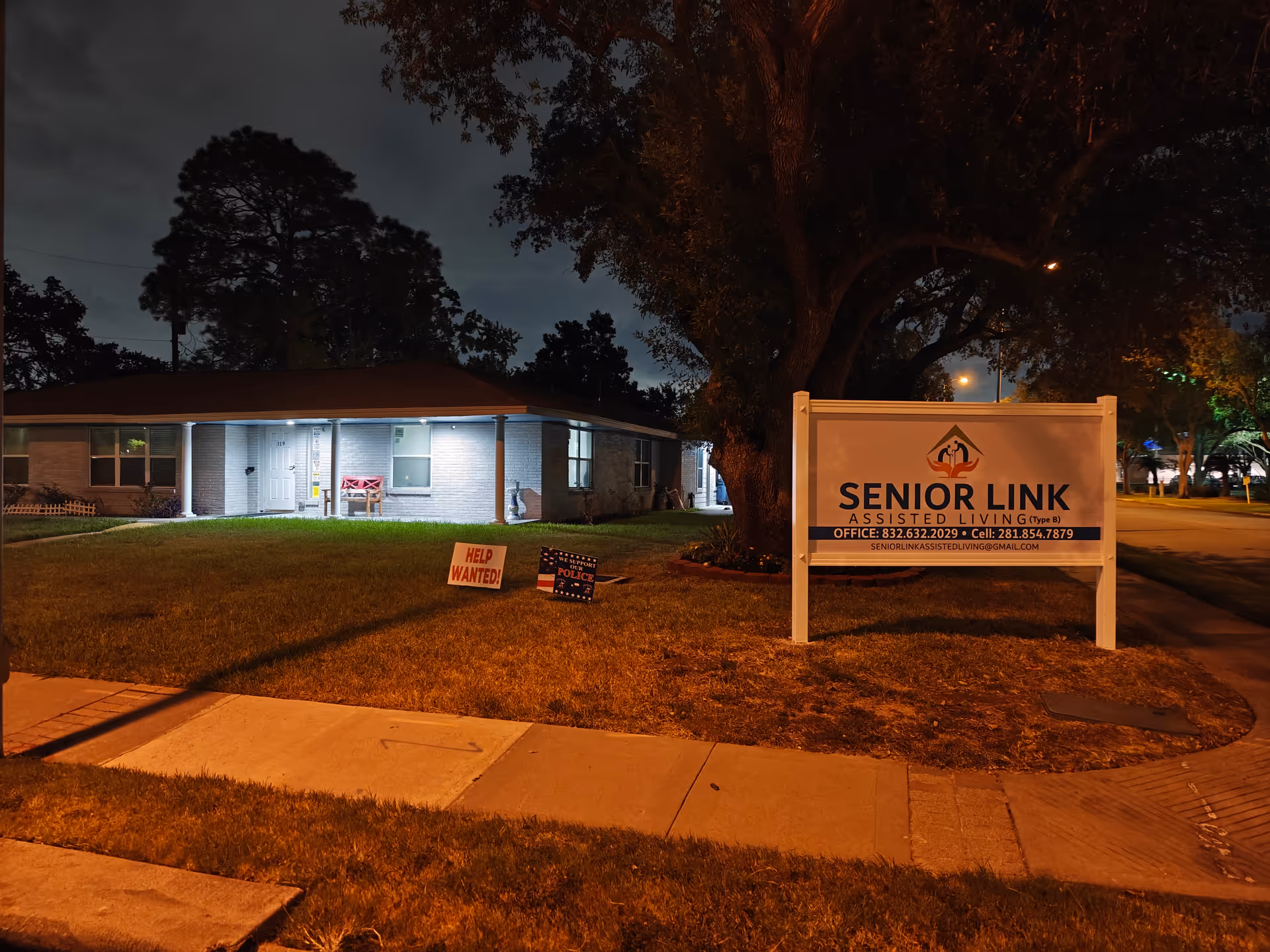 Night exterior of Senior Link Assisted Living with a large front sign and lit entrance.