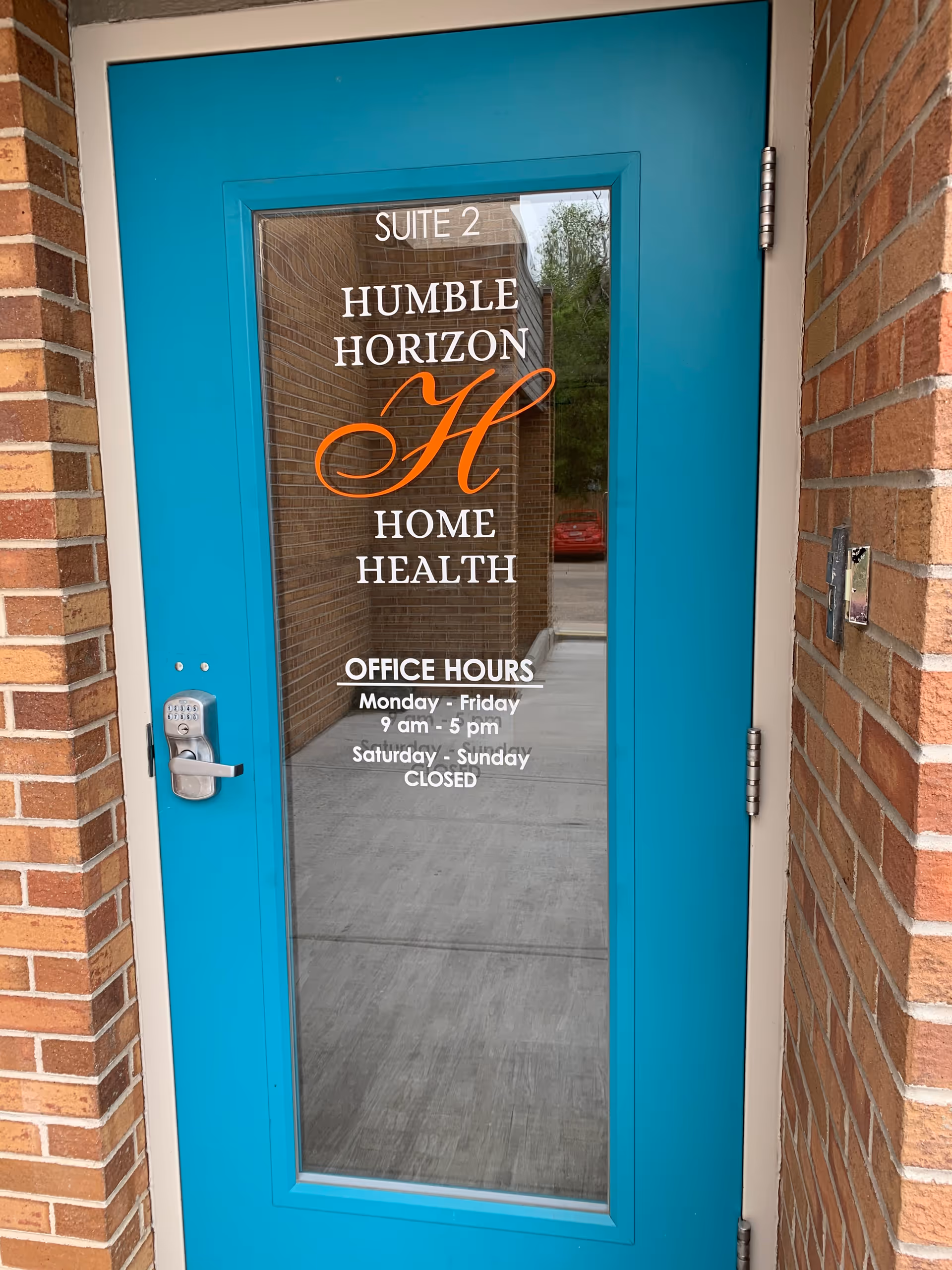 Turquoise glass door with Humble Horizon Home Health signage at brick building entrance.