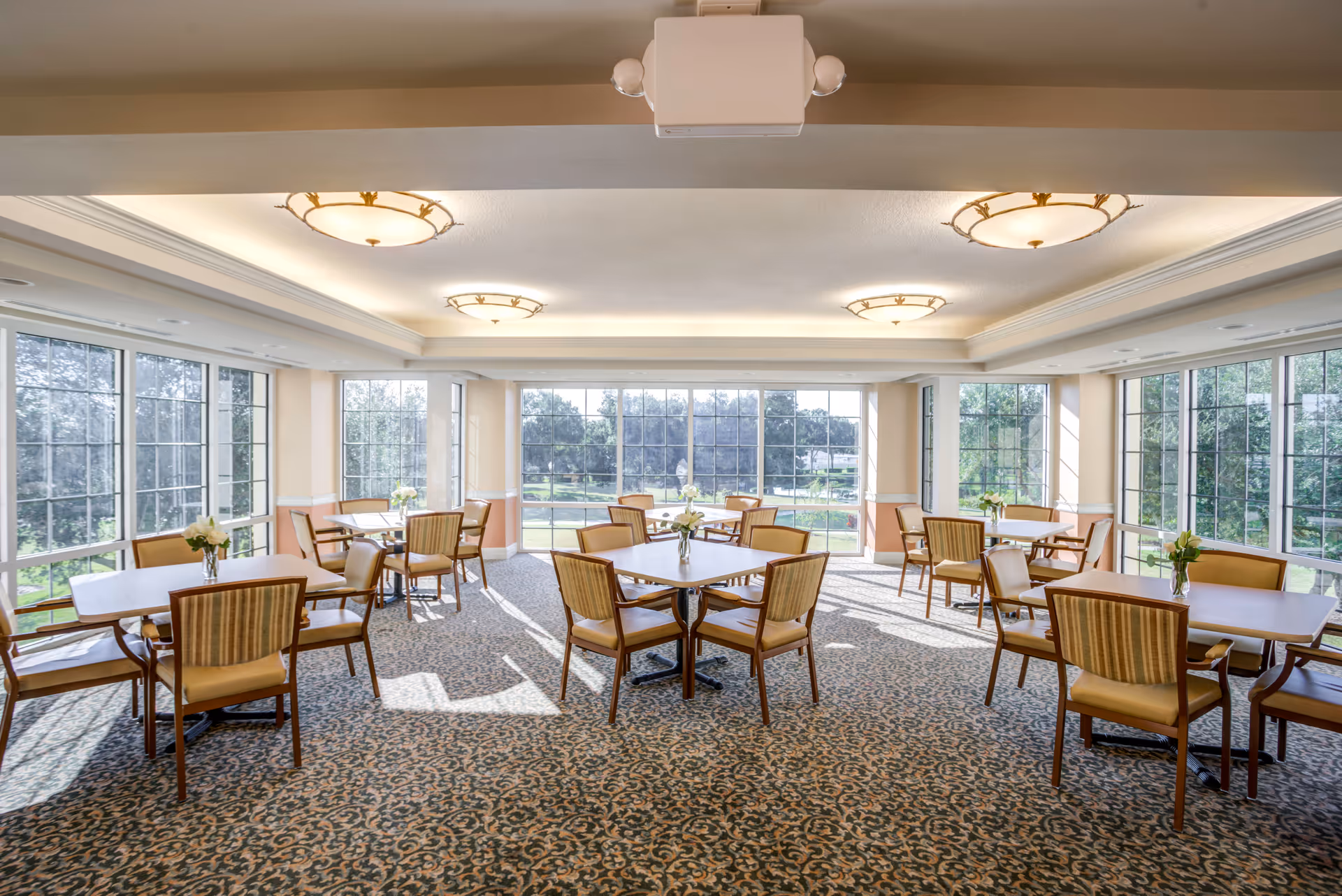 Bright dining room with multiple tables and chairs by large windows.