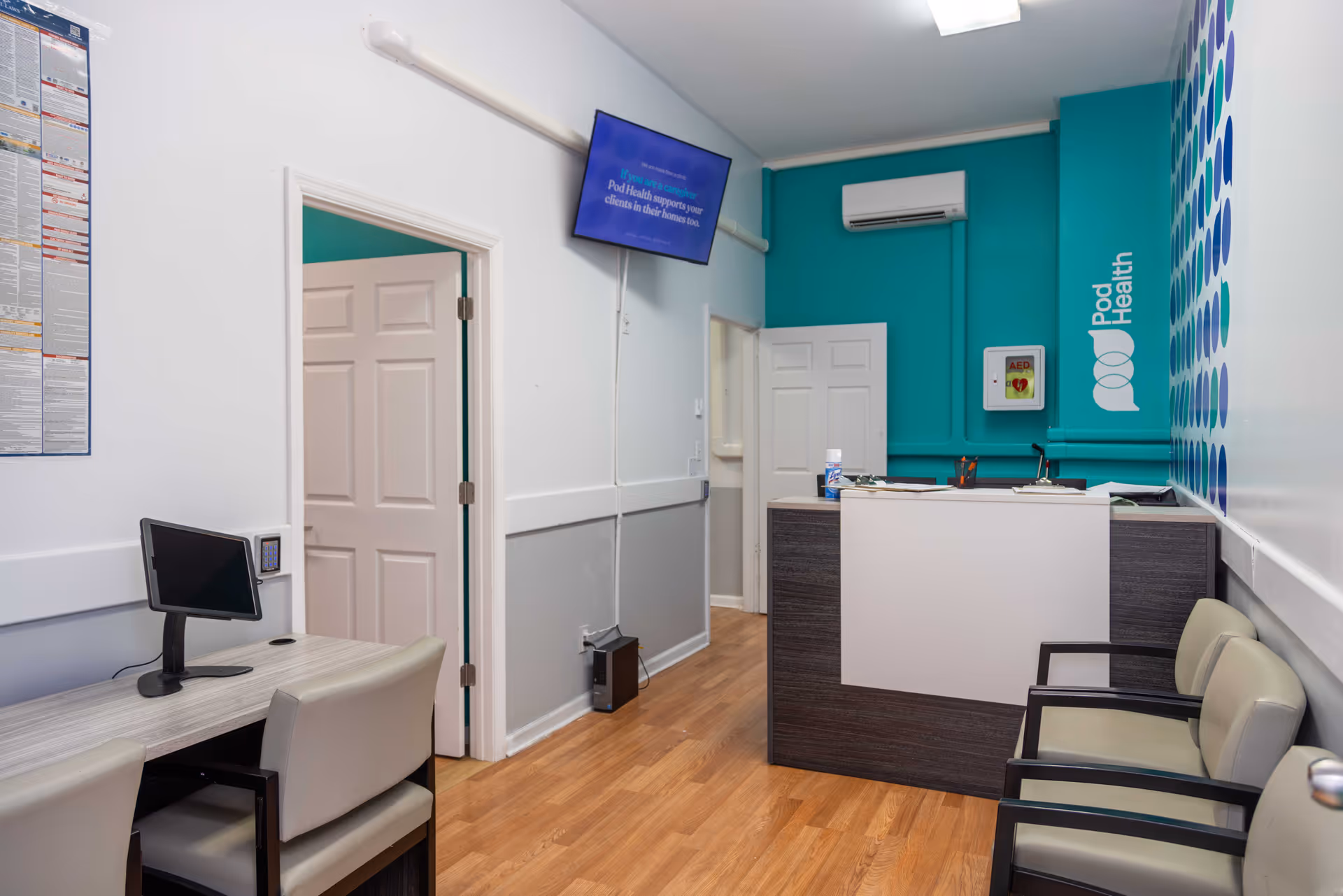 Reception desk with teal wall and waiting chairs in Pod Health facility lobby.