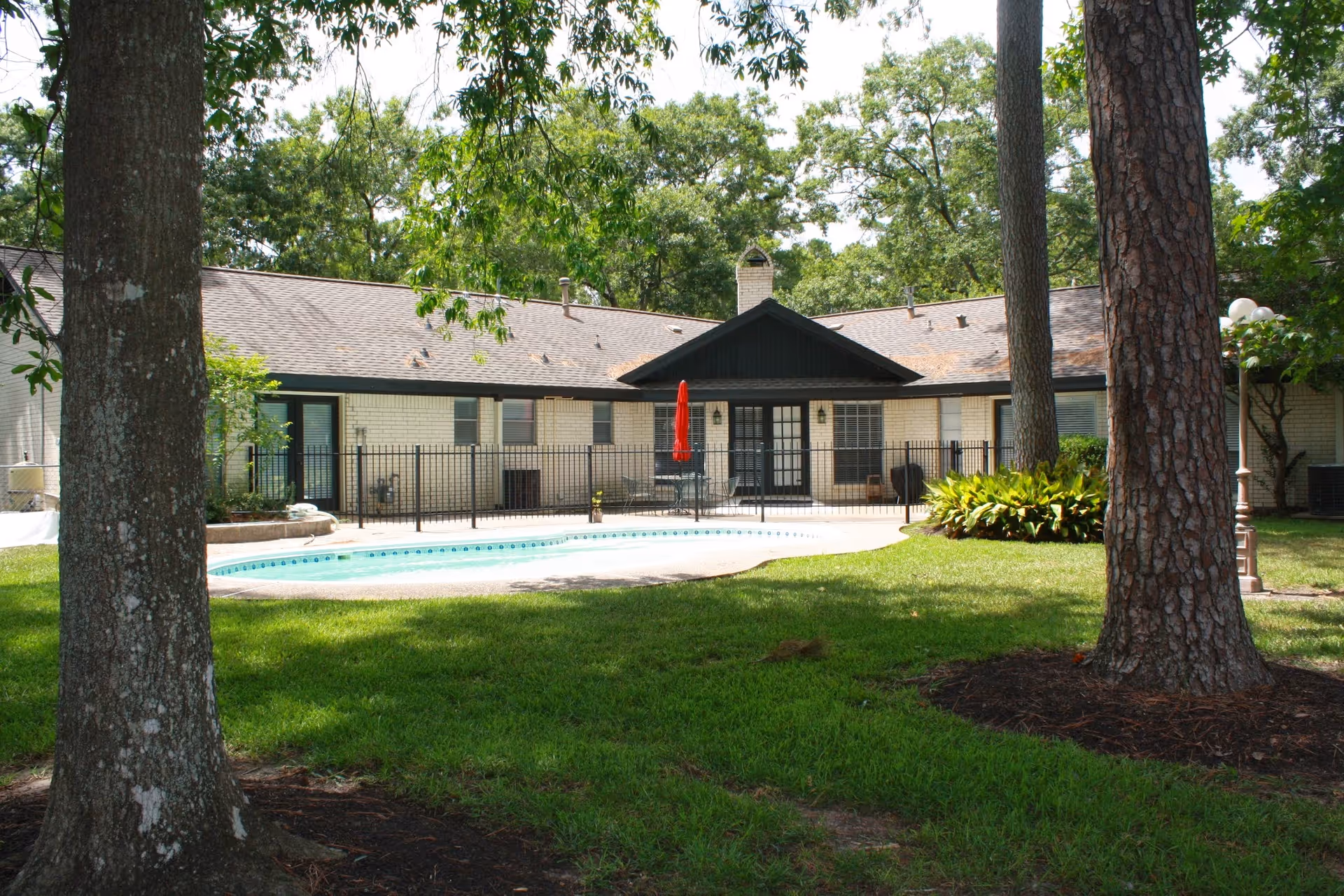 Exterior view of Assisted Living by Southwestern Care featuring a fenced pool and surrounding patio.