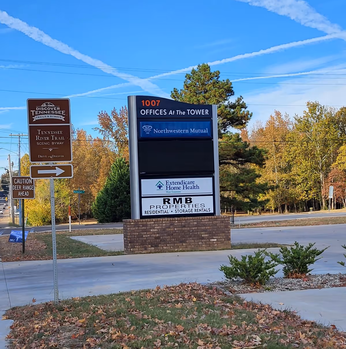 Exterior roadside sign displaying Extendicare Home Health of West Tennessee among autumn trees.