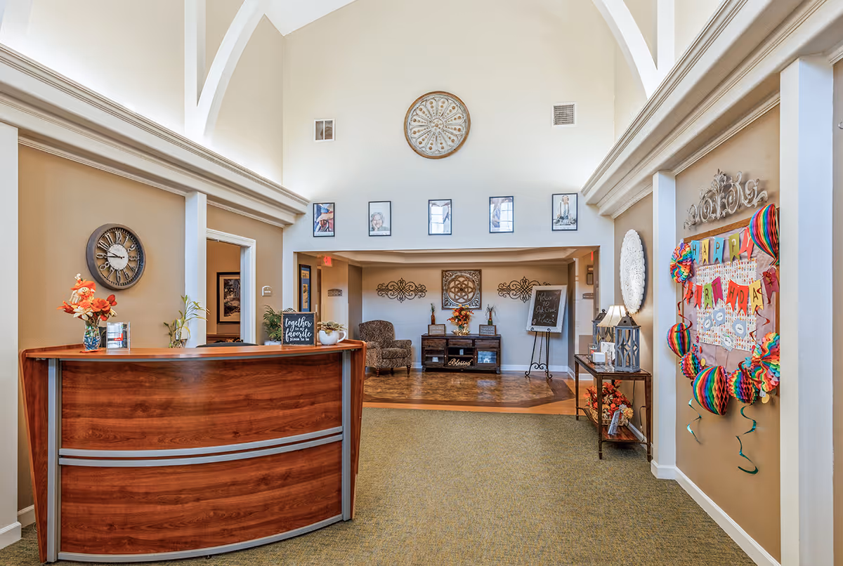 Warm lobby with curved wooden desk, seating, and birthday decorations.