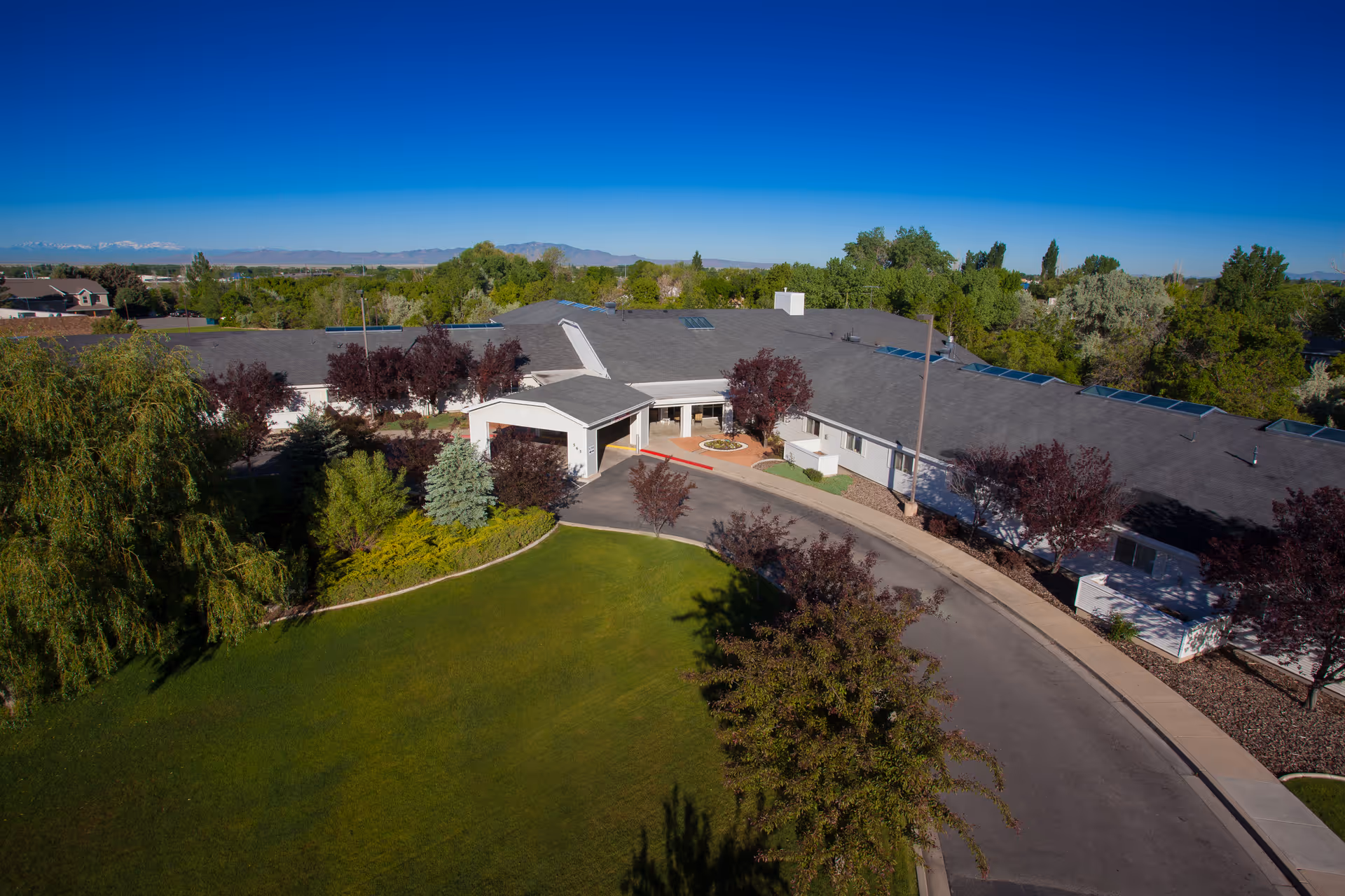Aerial view of Apple Tree Assisted Living campus with entrance, curved driveway, and trees.