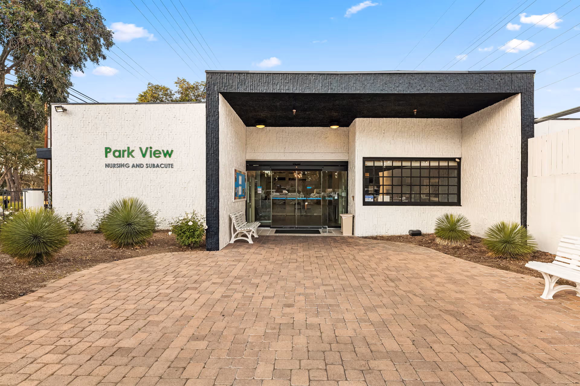 Front exterior of Park View Nursing and Subacute with glass entry and benches.