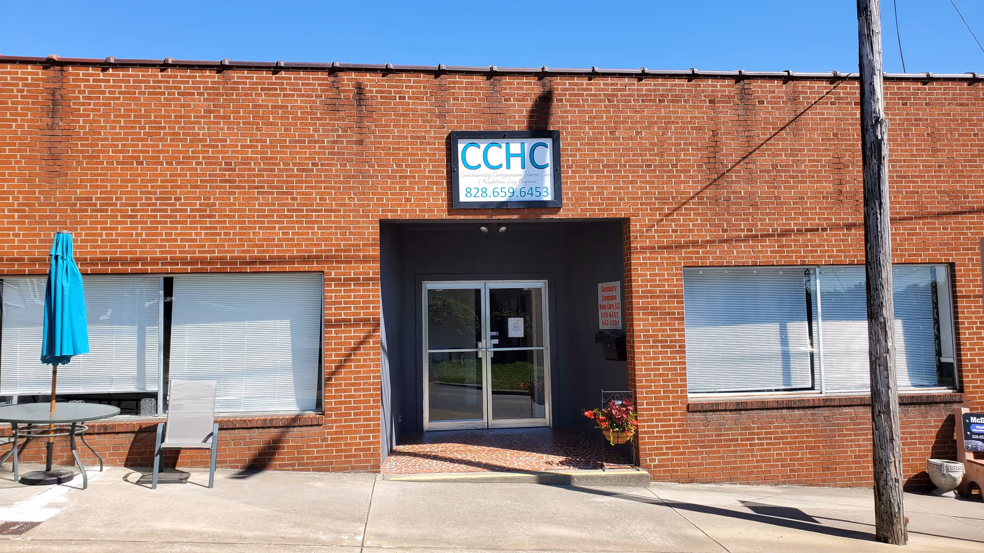 Brick facility facade with glass entry doors, CCHC sign, and outdoor seating.