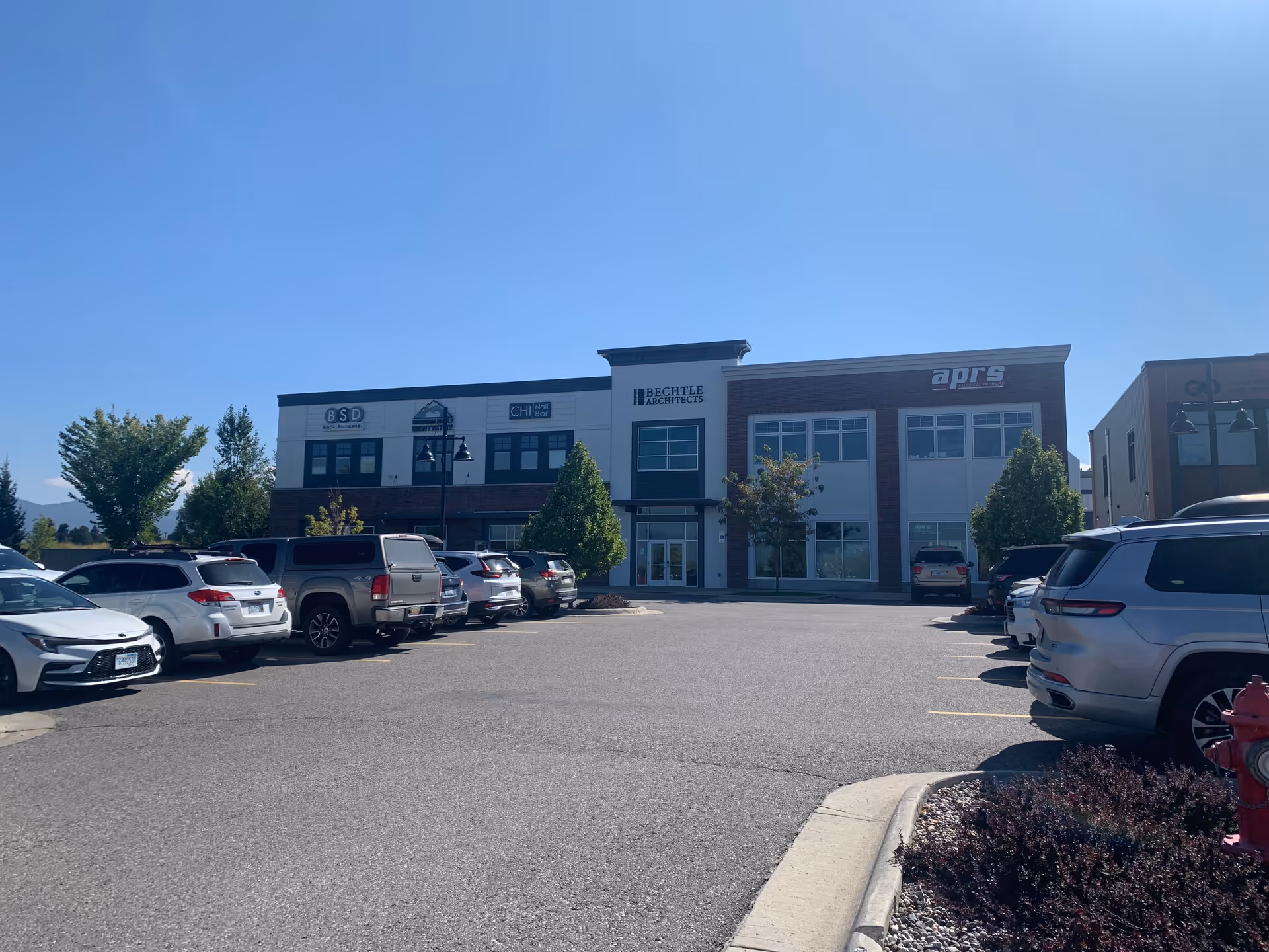 Exterior view of a modern commercial building with a parking lot and blue sky