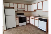 U-shaped kitchen with white cabinets, appliances, and a sink in a senior living facility.