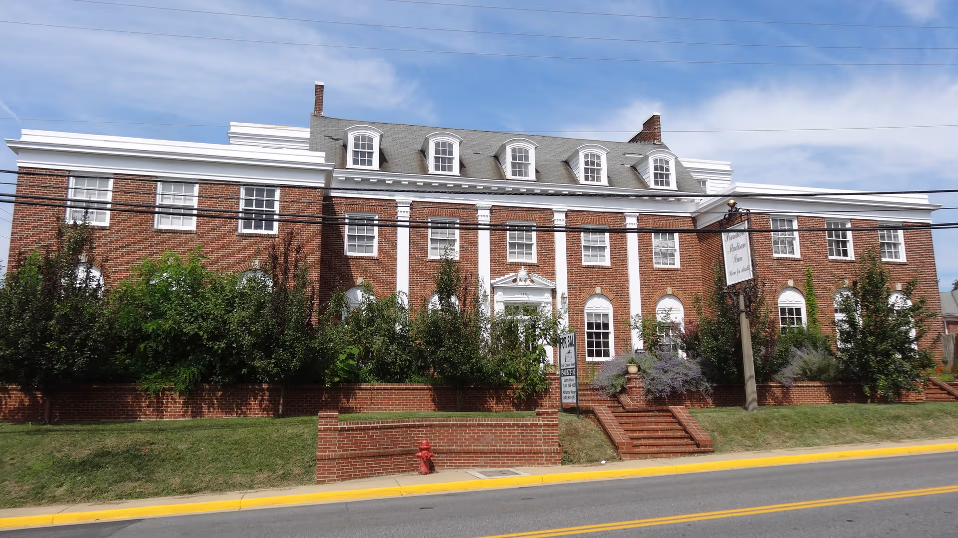 Brick senior living facility named President Madison Inn with white trim and dormer windows.