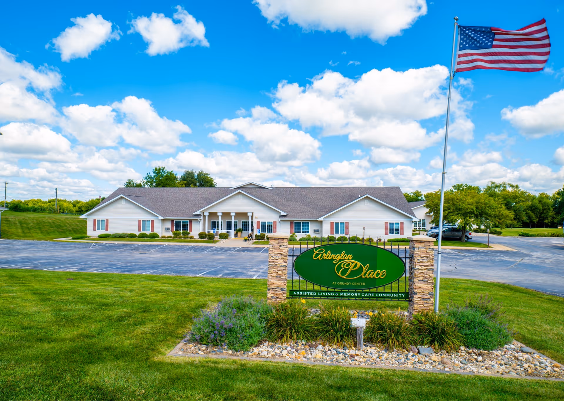 Single-story assisted living facility with Arlington Place sign and waving American flag.