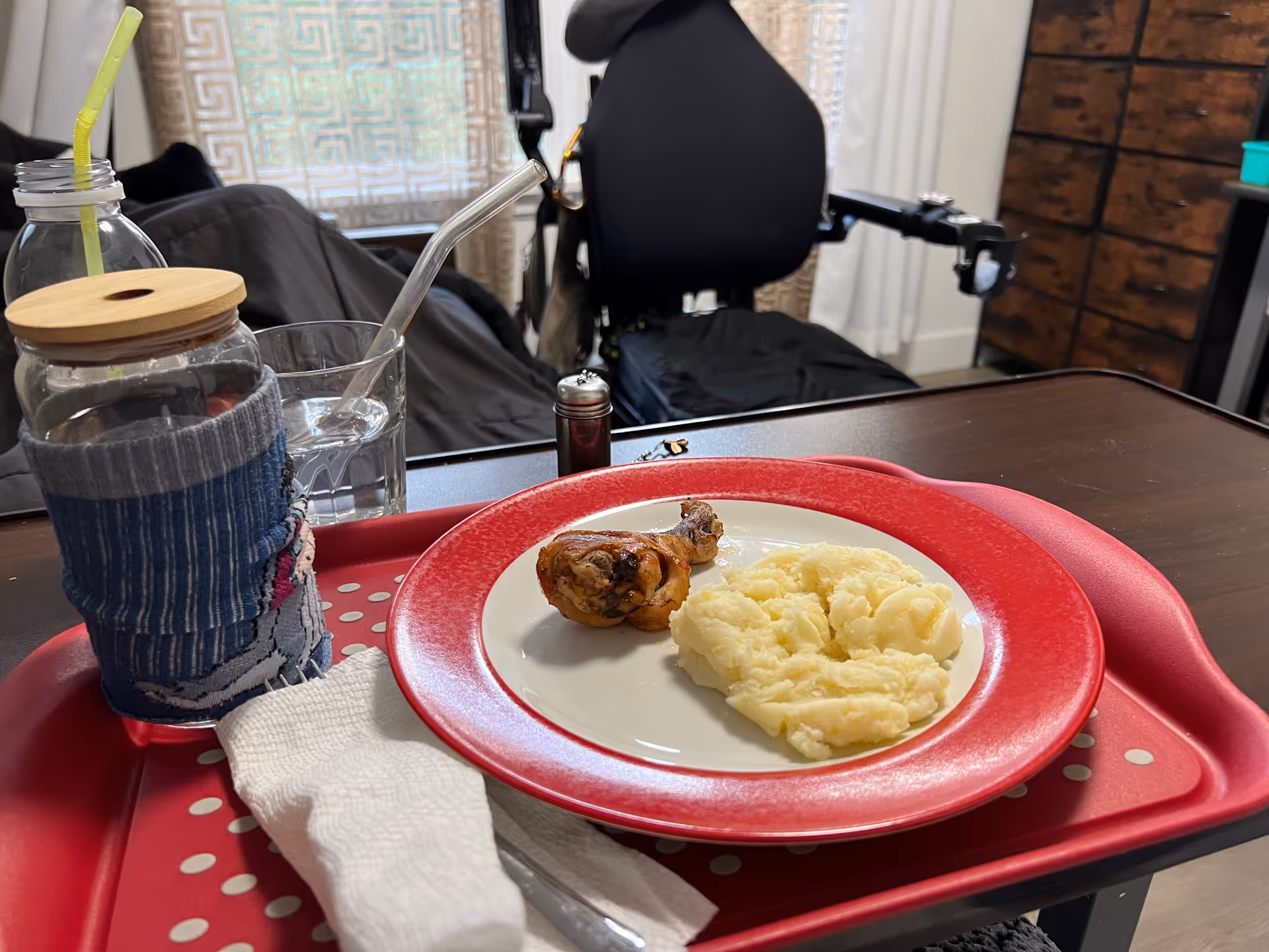 Tray meal with mashed potatoes and roasted chicken on a red plate in a resident room