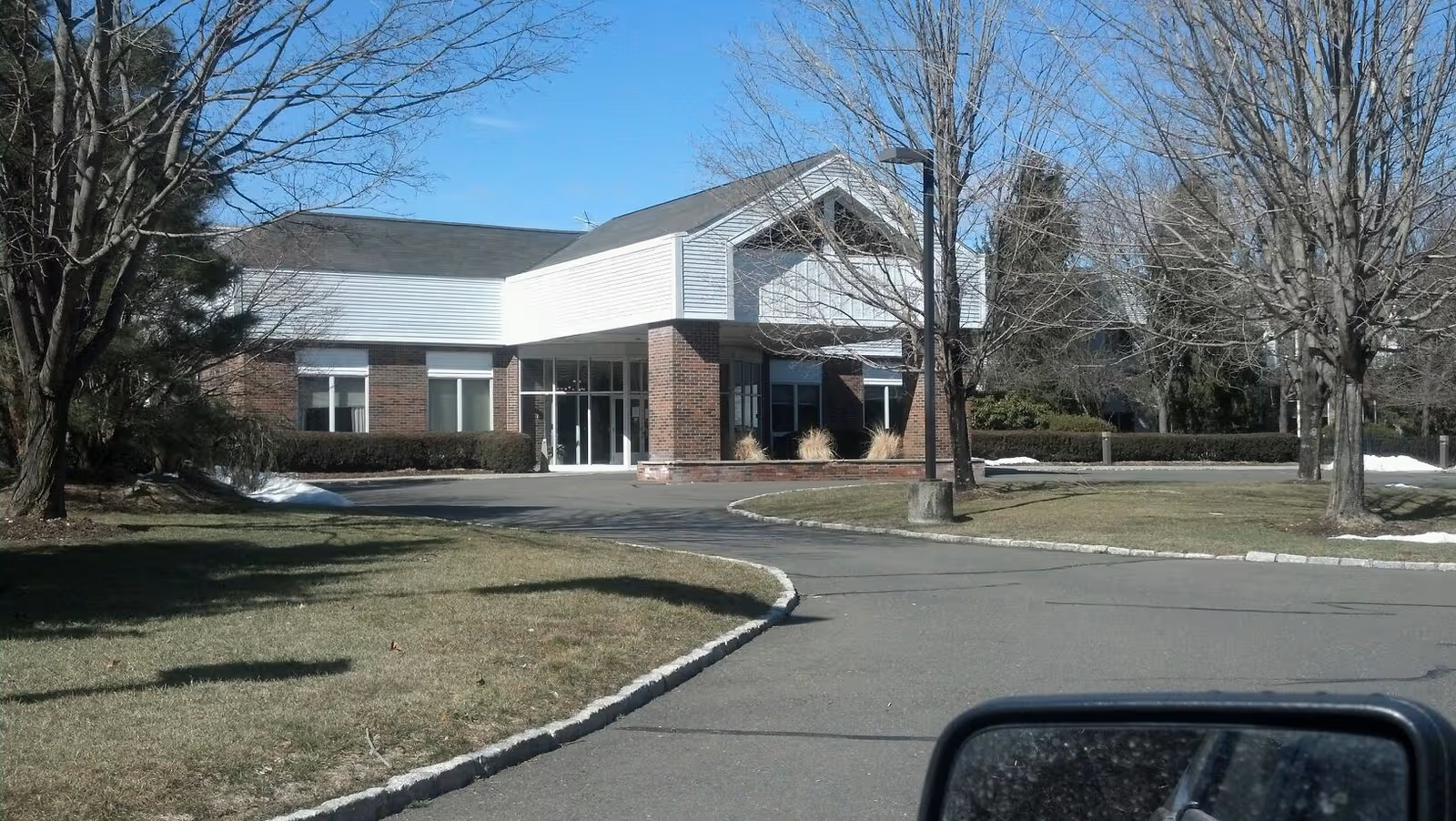 Front view of Wilton Meadows Nursing and Rehabilitation entrance with curved driveway and bare trees.