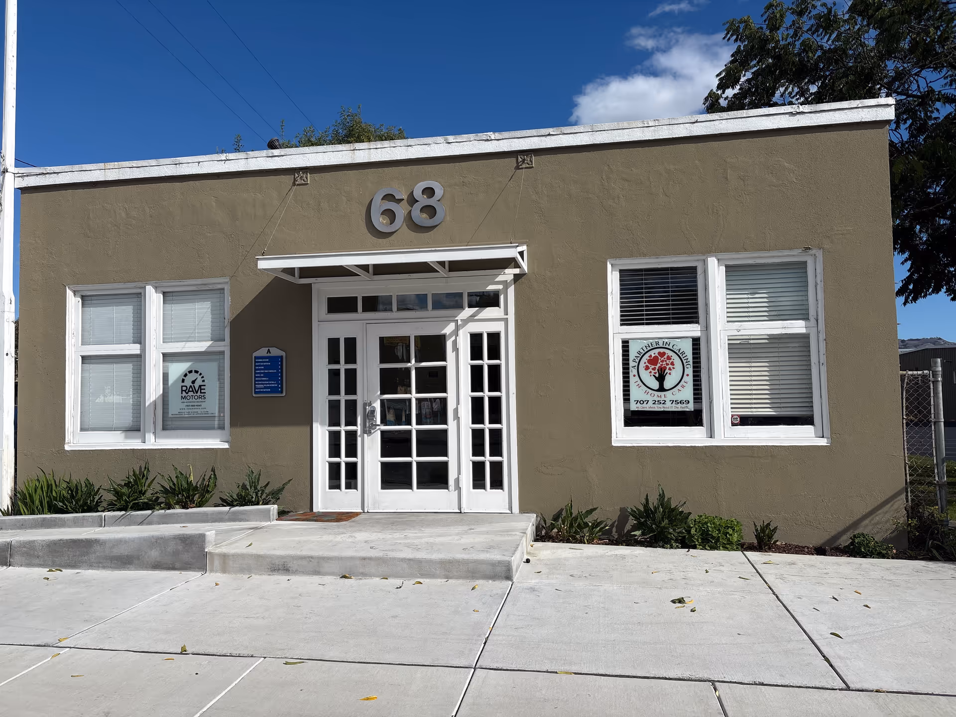 Beige, single-story building front with glass double doors and the number 68.