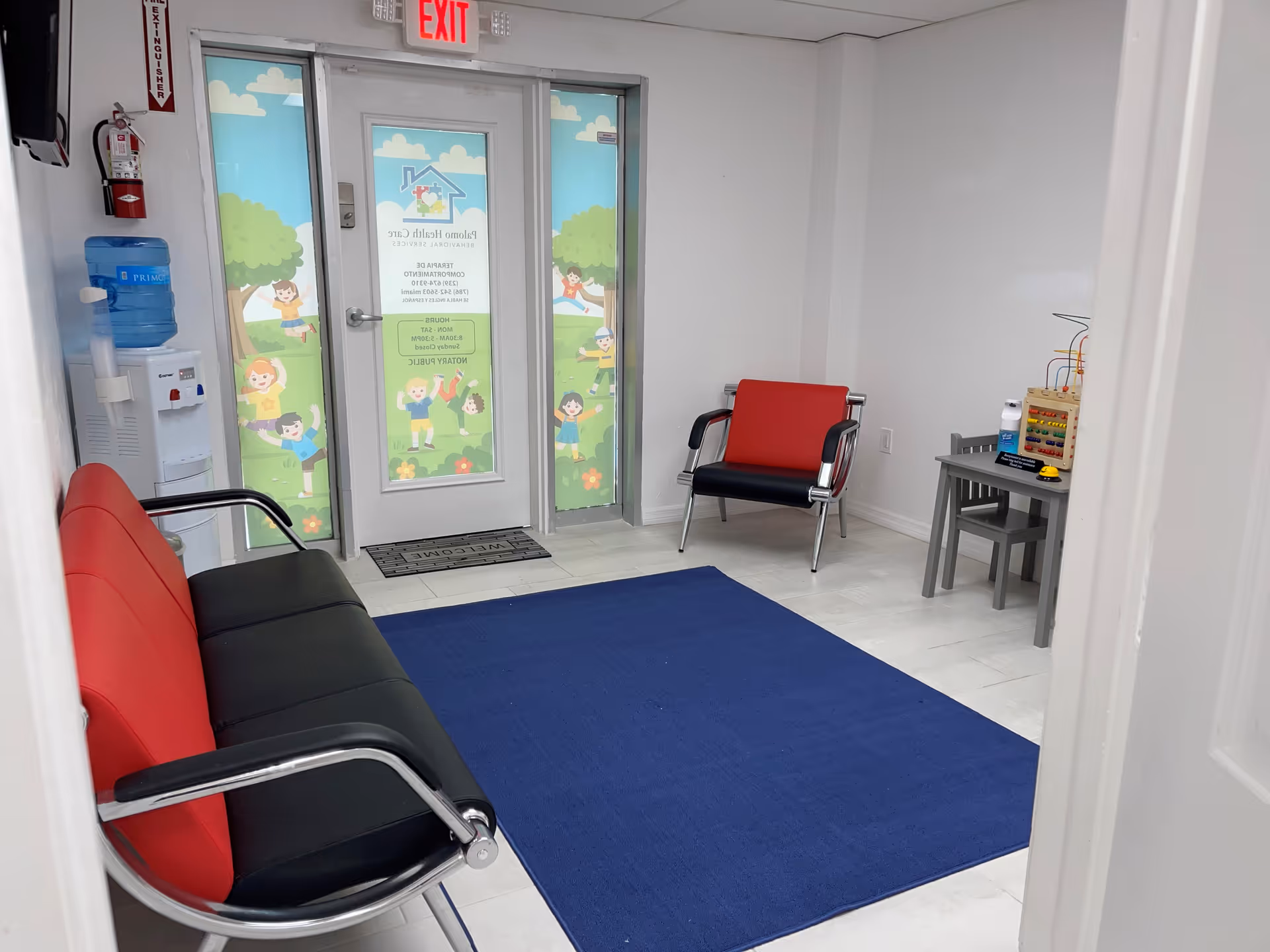 Interior waiting room with red and black chairs, blue rug, and a bead maze toy.