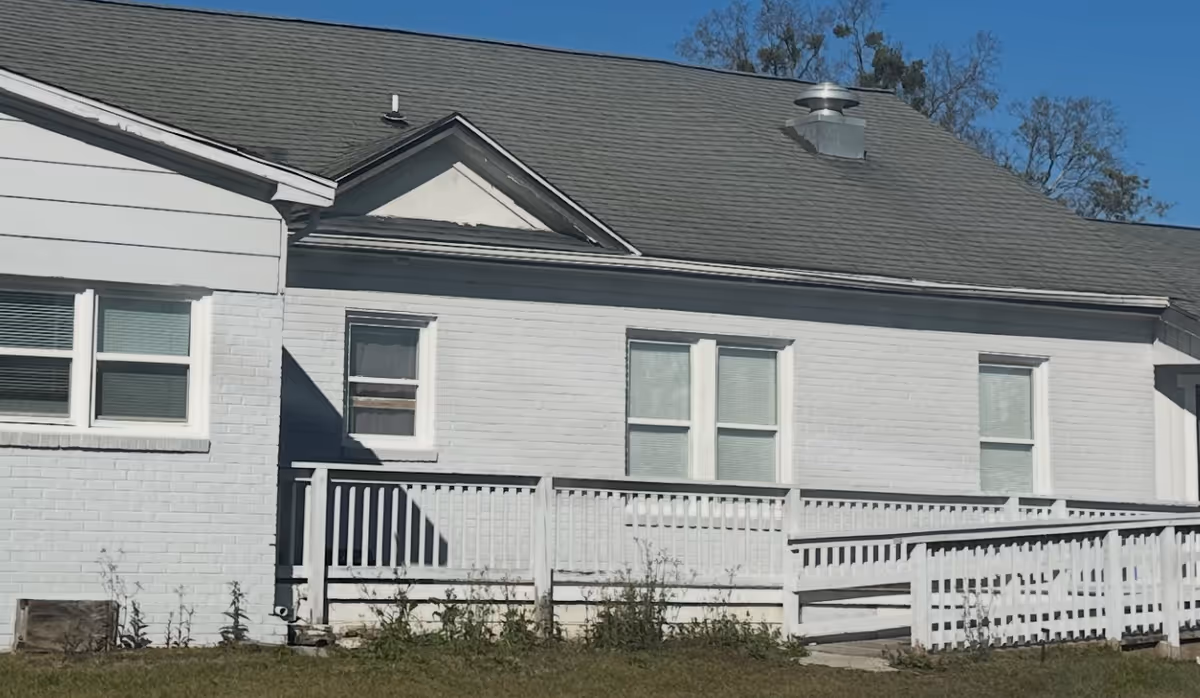 White brick senior living facility exterior with a ramp and railing.