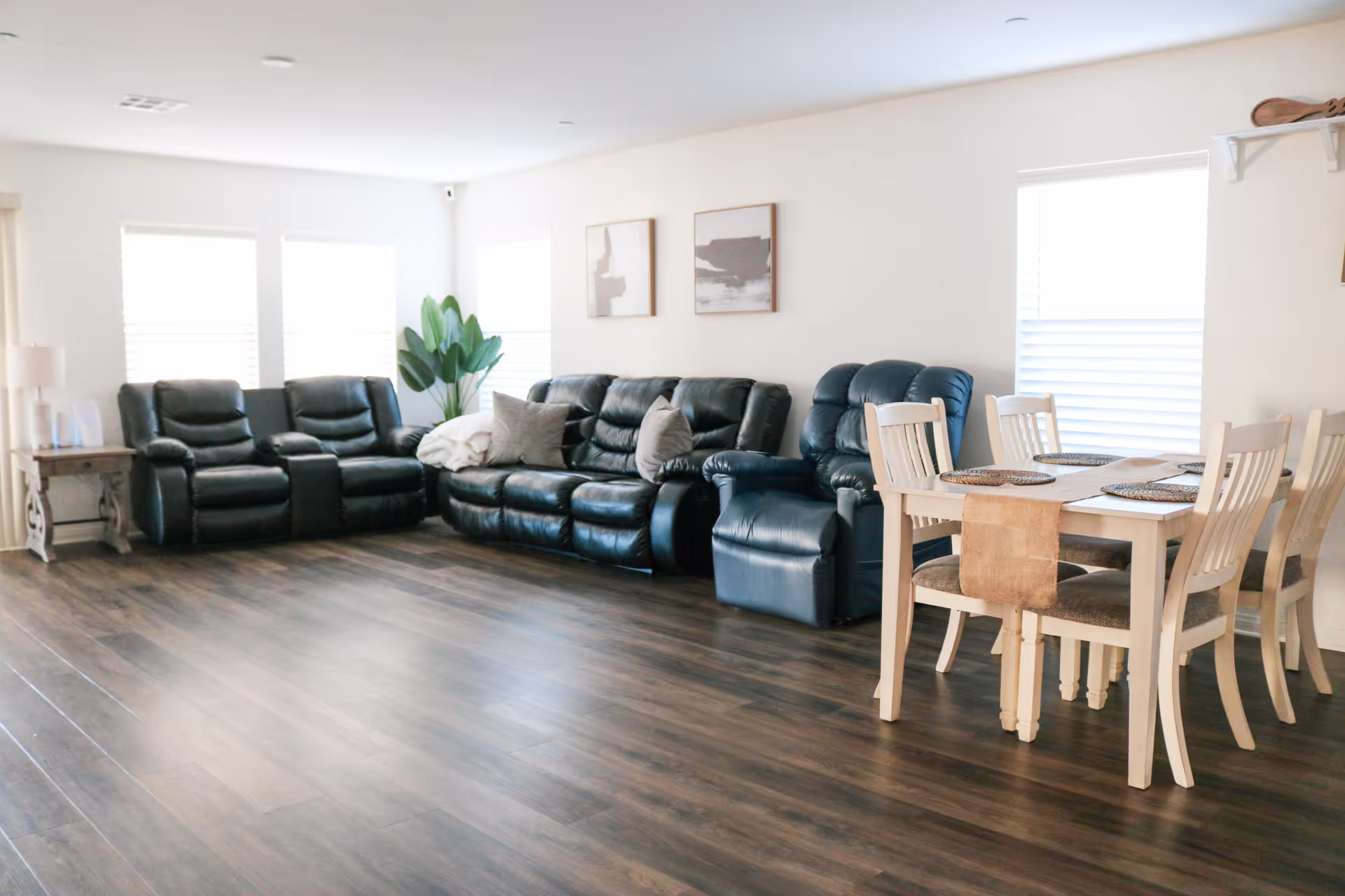 Bright living room in a senior facility with dark leather sofas and a dining table.