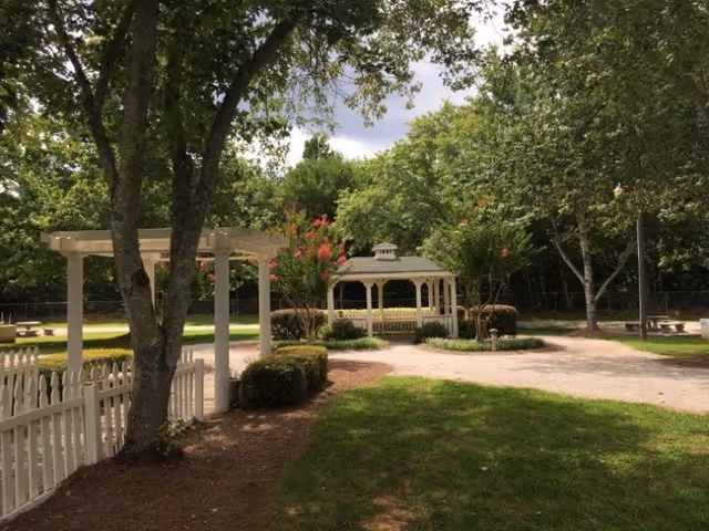 Outdoor garden at Lighthouse Manor with white gazebos, pathways, benches, and trees.