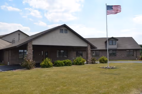 Pine Ridge Health and Rehab building with flagpole, brick exterior, and manicured lawn.