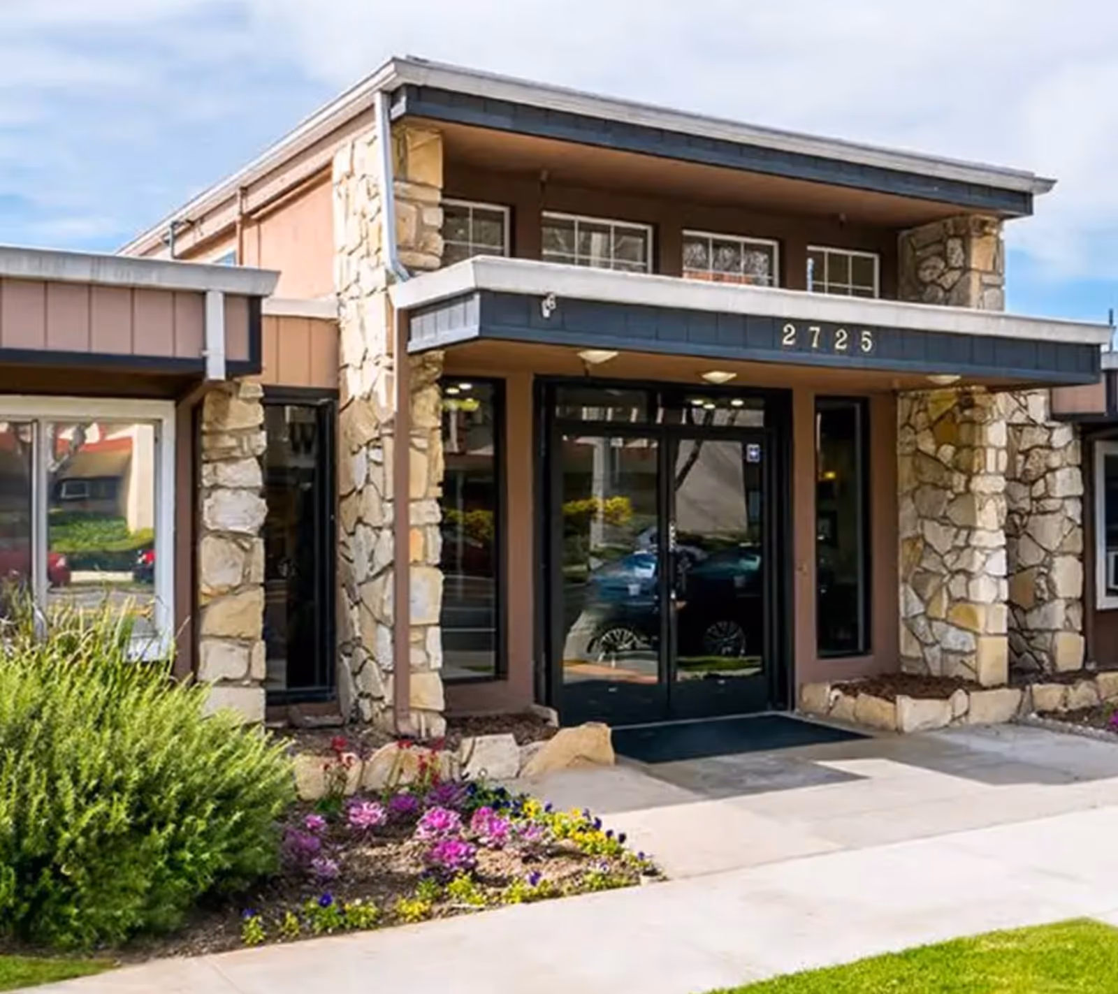 Exterior view of Royal Care Skilled Nursing Center entrance with stone pillars and glass doors.
