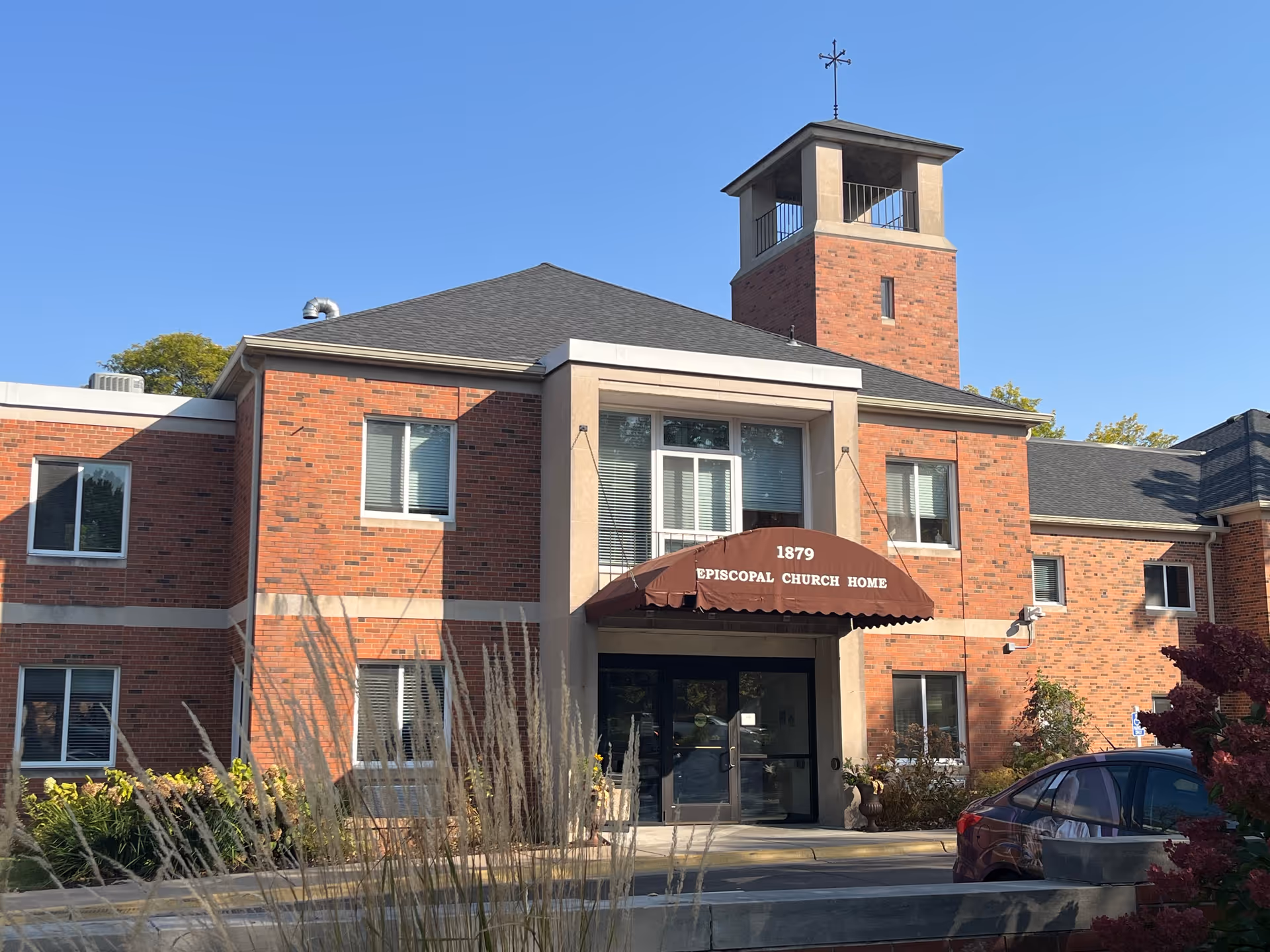 Brick building with a front entrance and awning labeled Episcopal Church Home.