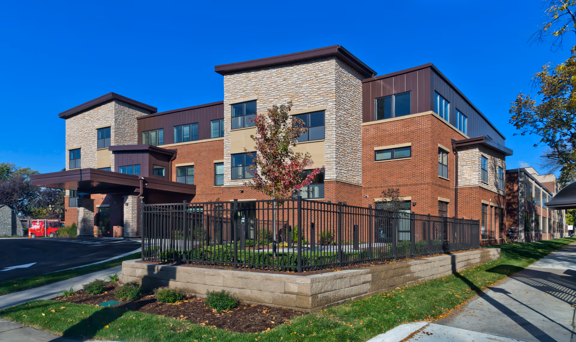 Exterior view of a modern brick-and-stone senior living facility with landscaping.