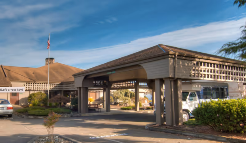 Entrance to Channel Point Village senior living with a covered entry and a parked bus