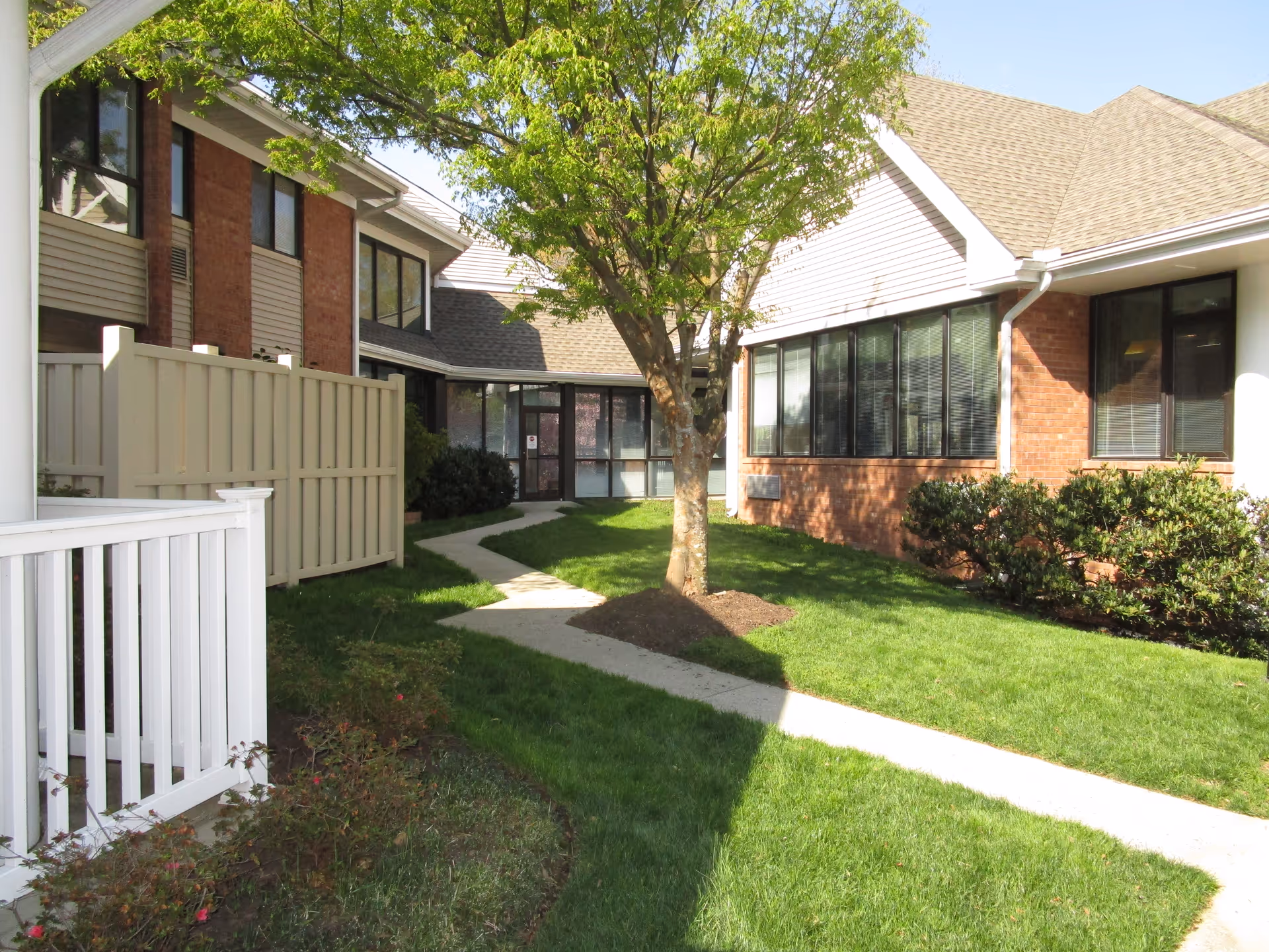Exterior view of a St. Mary's Woods building with a green lawn and central tree.