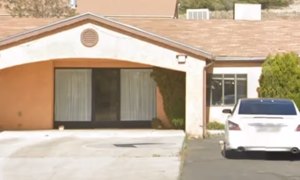 Front view of Sunset Vista Assisted Living facility with covered entrance and a parked car.
