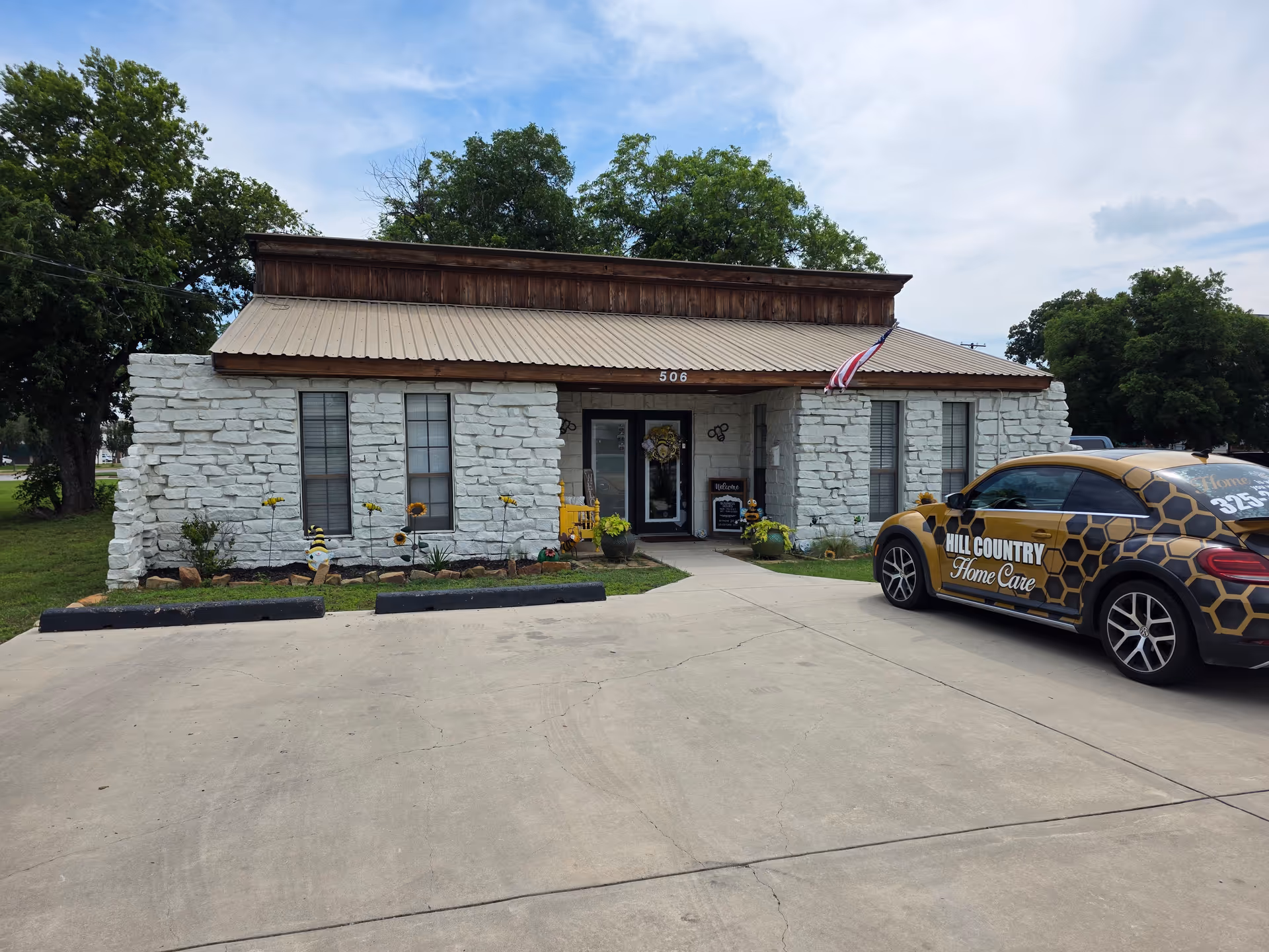Stone-faced building with a porch and Hill Country Home Care car parked out front.